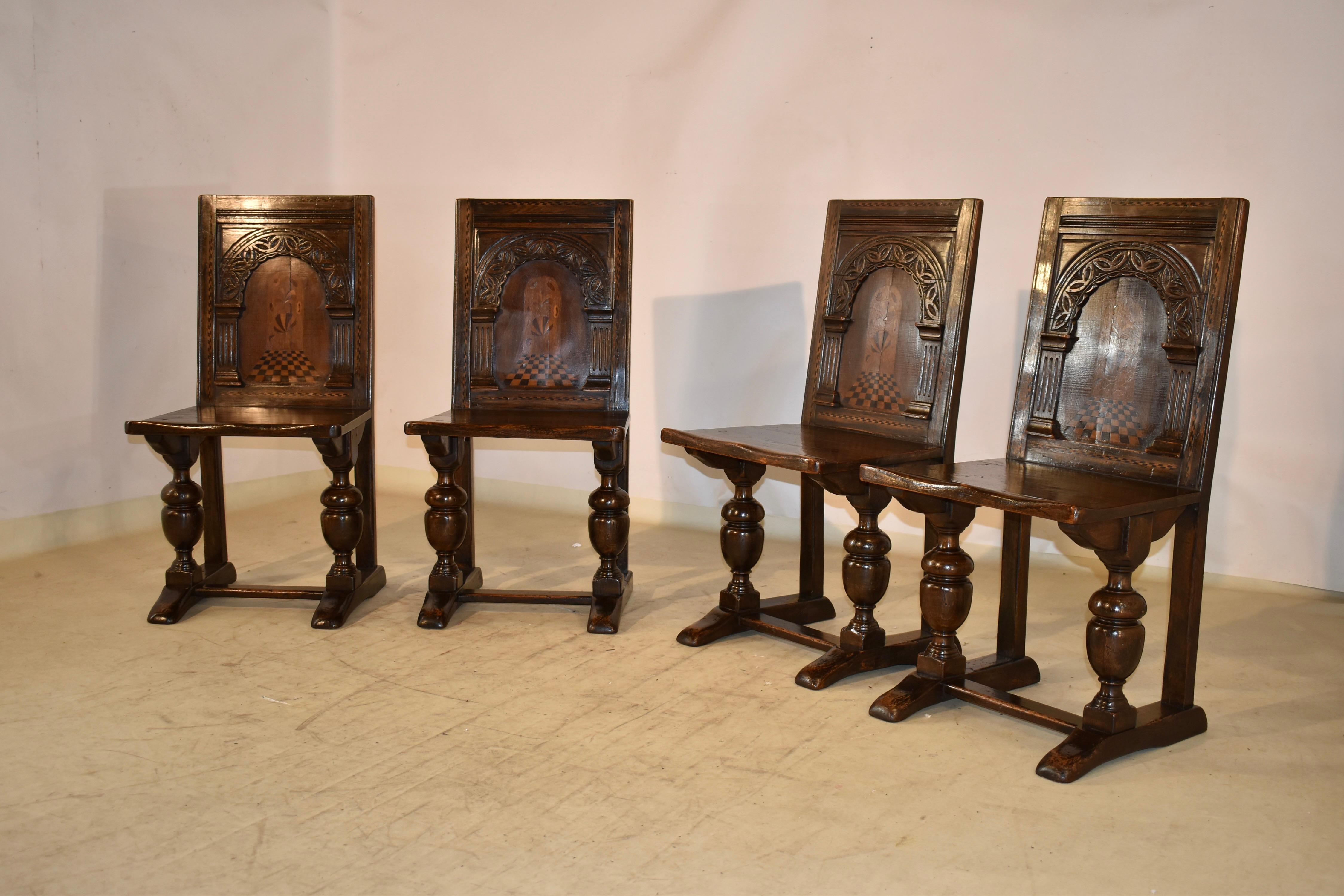 Set of four elegant English side chairs in oak, with fruitwood inlay.  The seat back has a hand laid border of inlaid barber pole inlay surrounding the central panel, which has hand carved and fluted arched columns over a central parquetry design,