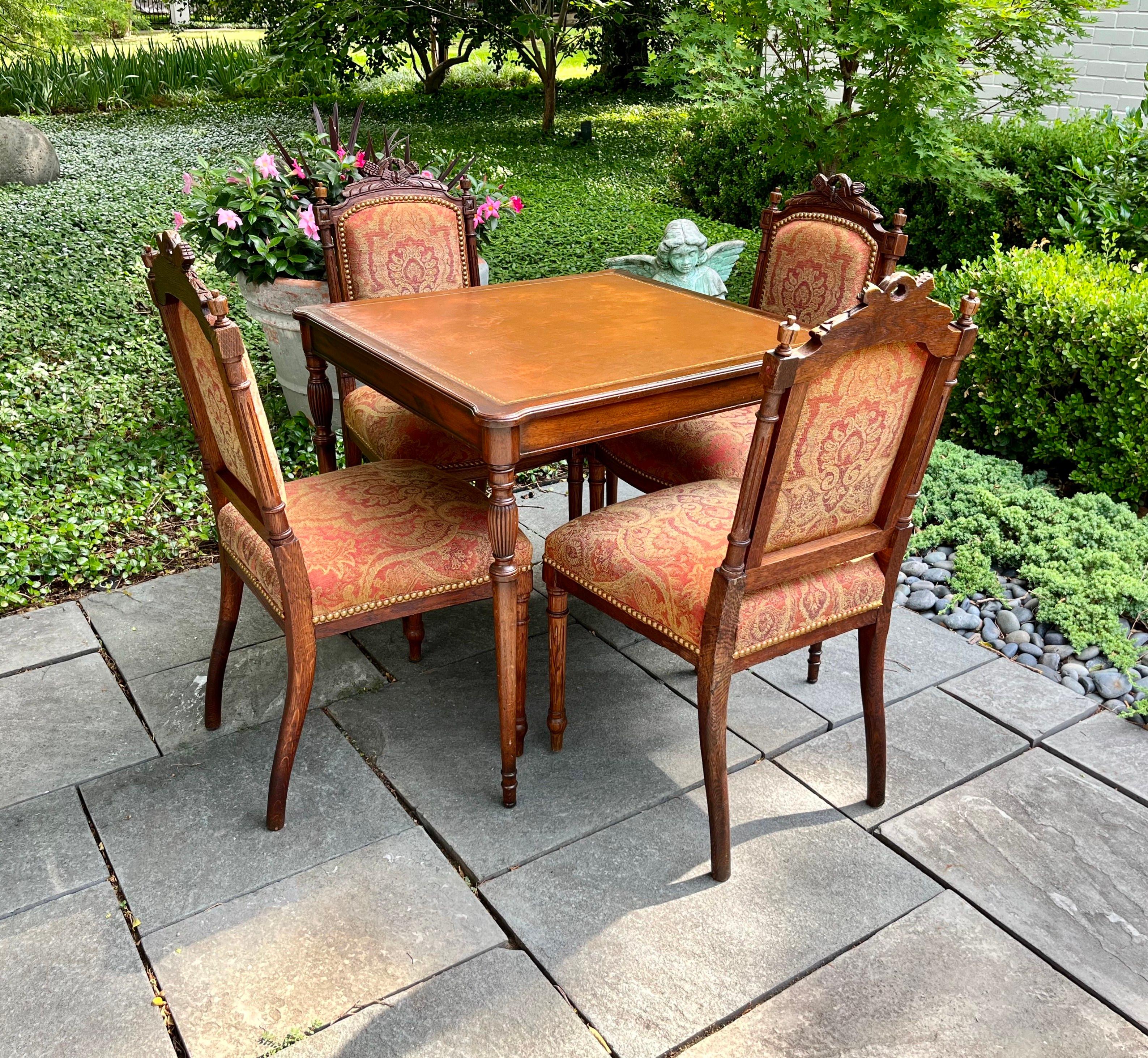This fine set of chairs and matching game table would be a beautiful addition to a living room, study, or game room. The antique Louis XVI style chairs, crafted in France circa 1910, are carved of walnut with intricate detail. Each chair stands on