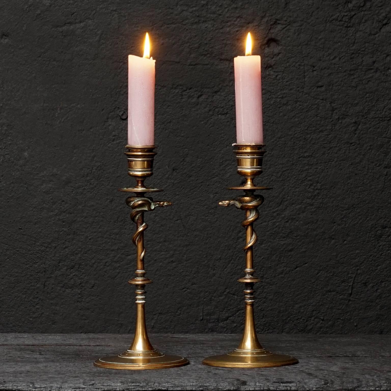 A pair of bronze candlesticks resting on a circular moulded base adorned with snakes crawling upwards.
Marked F. Barbedienne on the base. Numbered 46244 underneath and signed.

Ferdinand Barbedienne (1810-1892) was a renowned French metalworker
