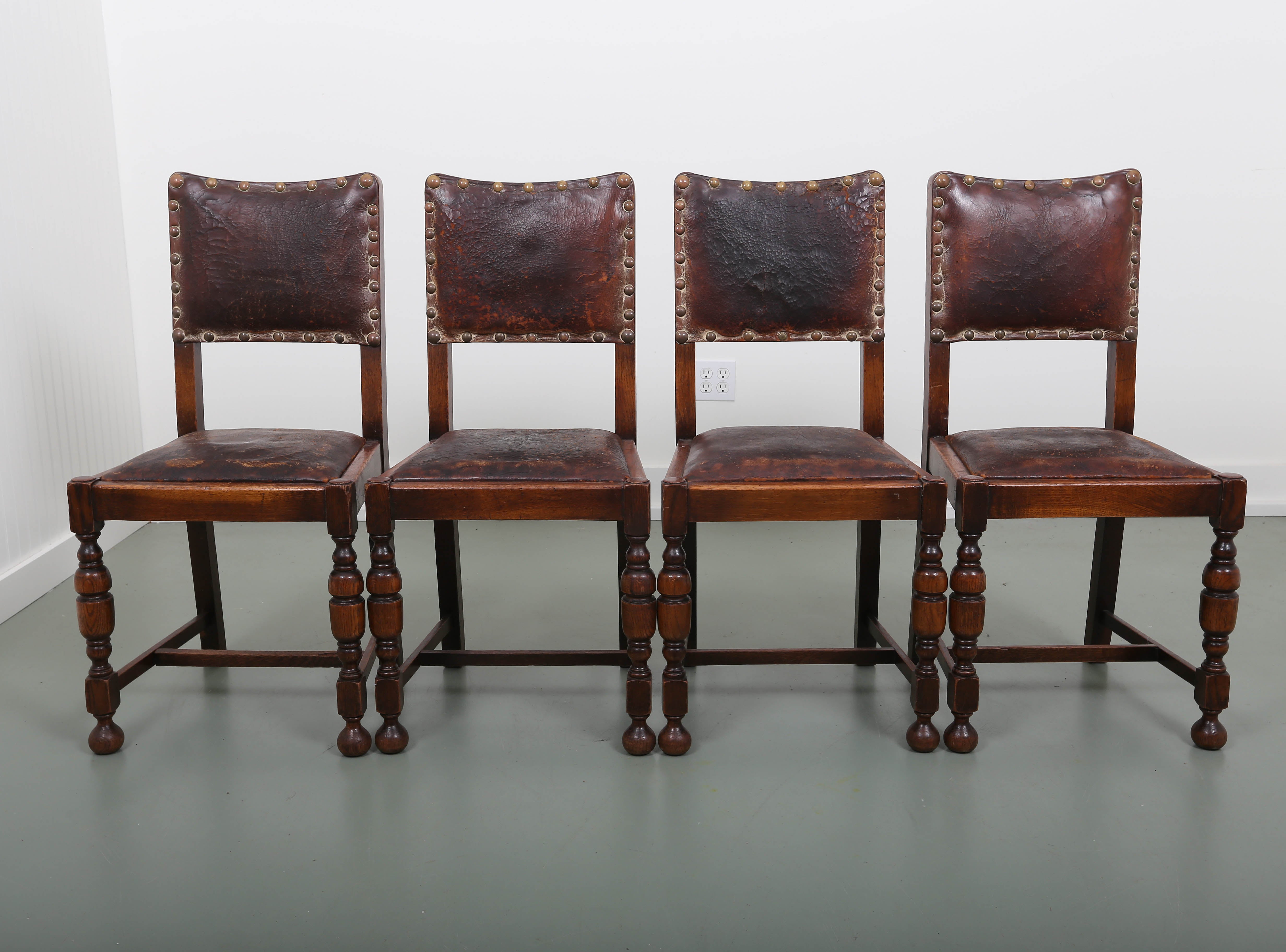 19th century set of four English oakwood dining chairs with leather. Leather in original condition with brass nailheads.