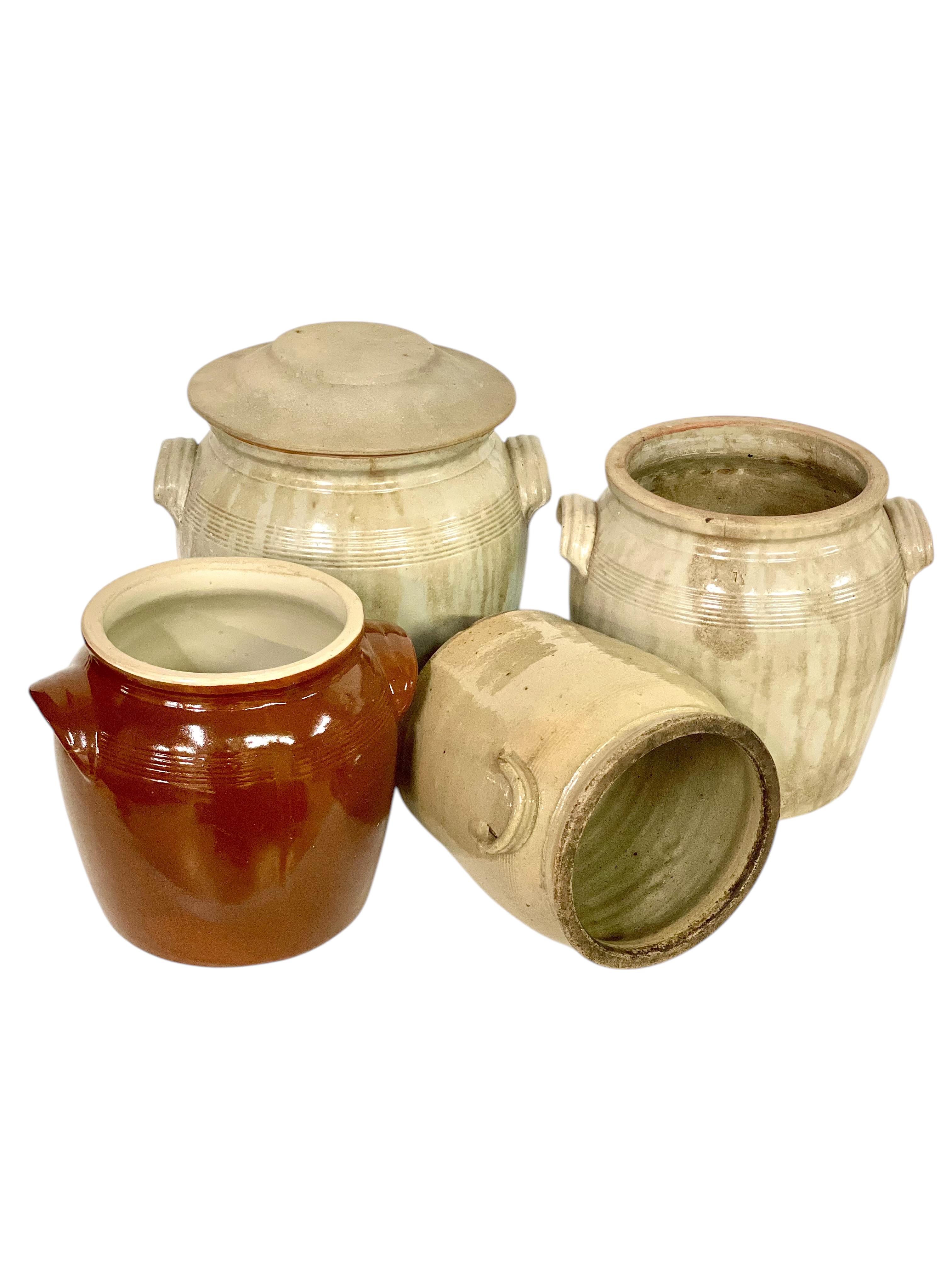 Cet ensemble de quatre pots à graisse français anciens met en valeur le charme et l'utilité de la poterie rustique du XIXe siècle. Ces pots en terre cuite étaient traditionnellement utilisés dans les ménages ruraux pour stocker la graisse animale