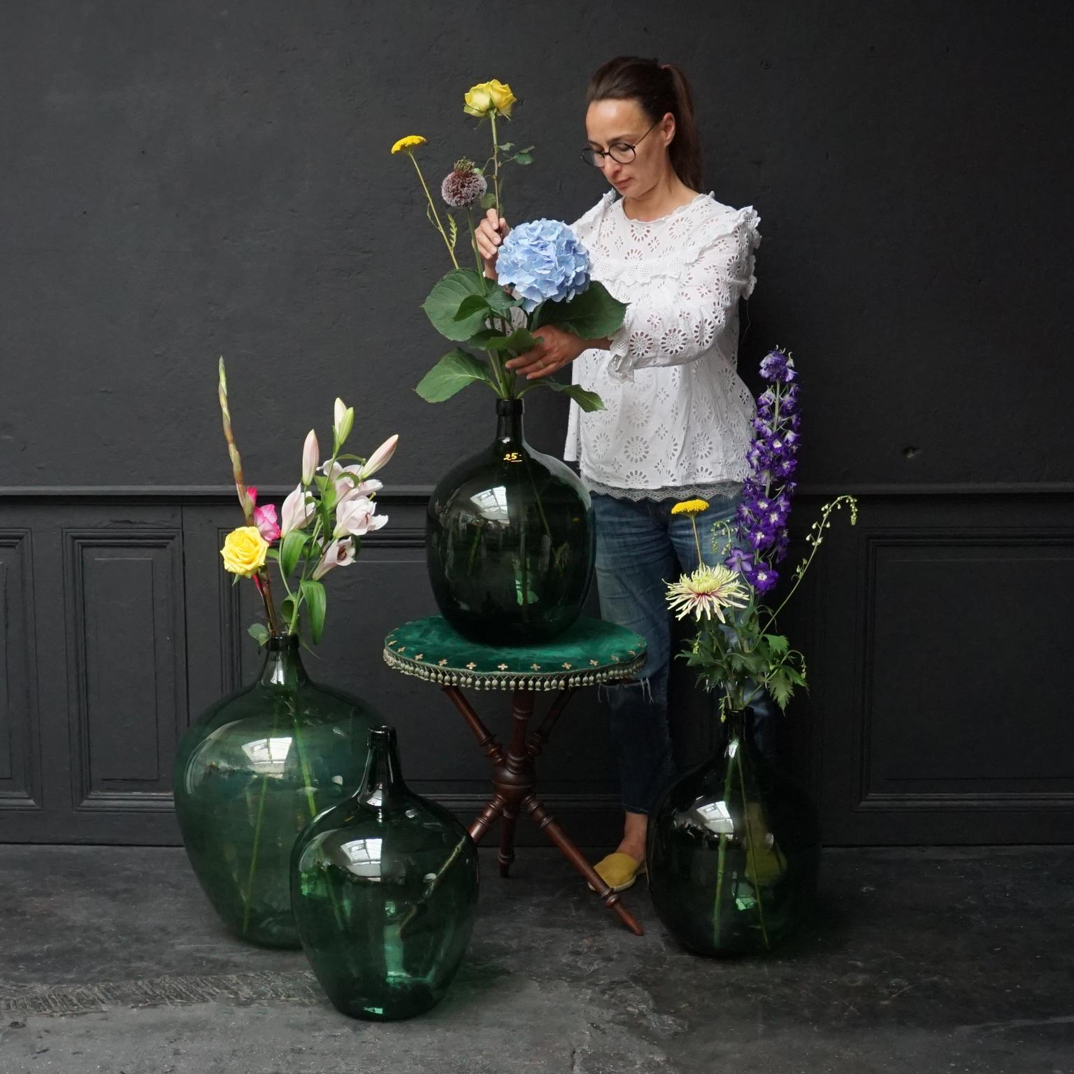 Very decorative set of 4 antique green hand blown and glass bottles also known as Demijohn, Lady Jeanne, Dame Jeanne or Carboy.

The three smaller ones of them have a capacity of 25 Litres, one is even marked on the ring with '25' this is