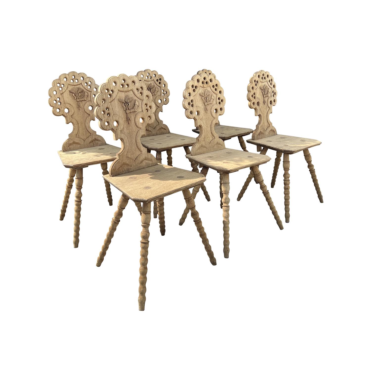 A set of six antique Italian dining room chairs made of hand crafted solid Pinewood. The backrest are carved with cut-outs and the legs are turned. In original condition with visible wear and heavy patina. Wear consistent with age and use, overall