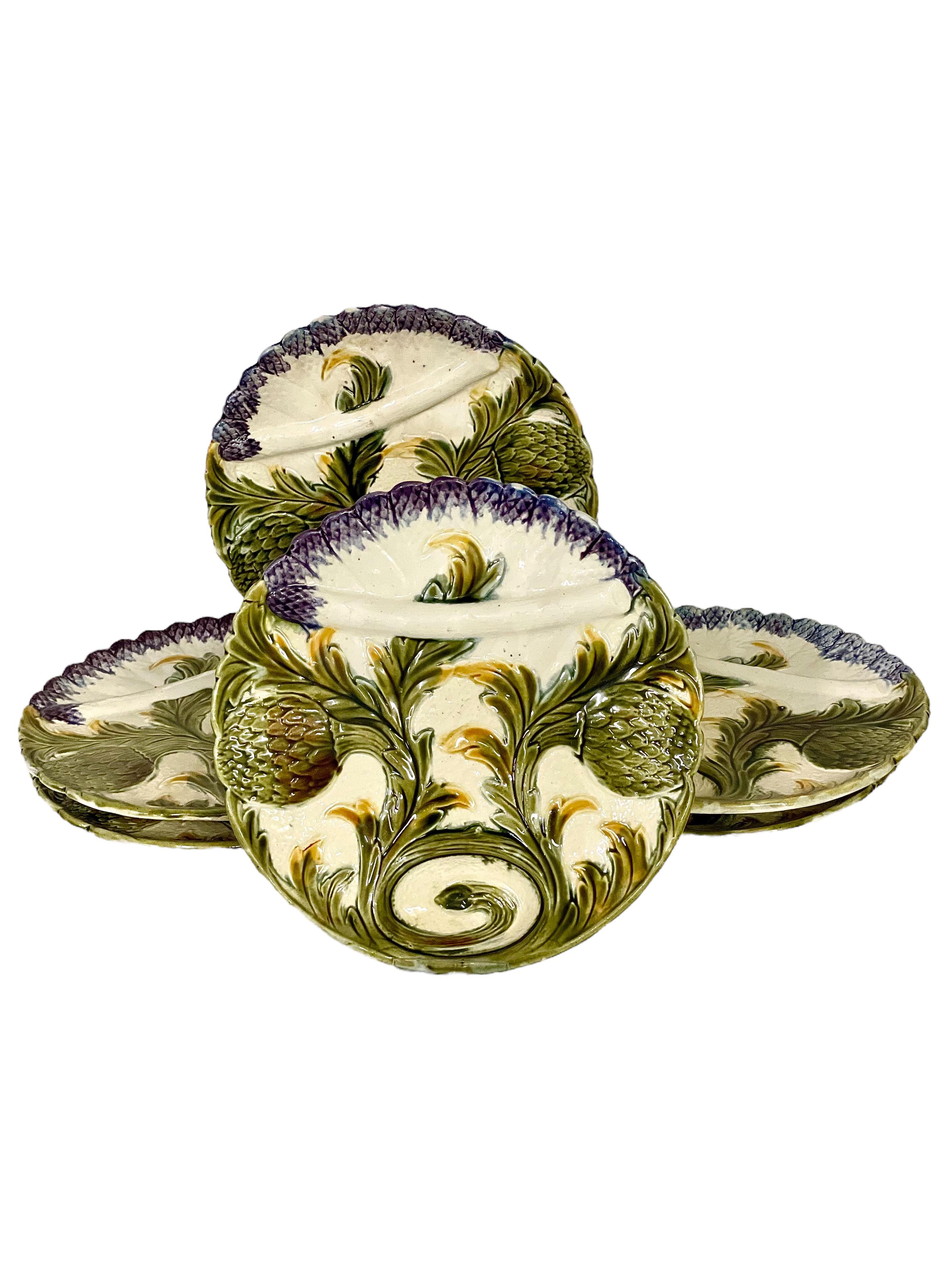 A very unusual and beautiful set of six French barbotine majolica asparagus serving plates, featuring a typical 'trompe l'oeil' textured decoration of globe artichokes and purple asparagus tips, artfully entwined with each other to create a pleasing