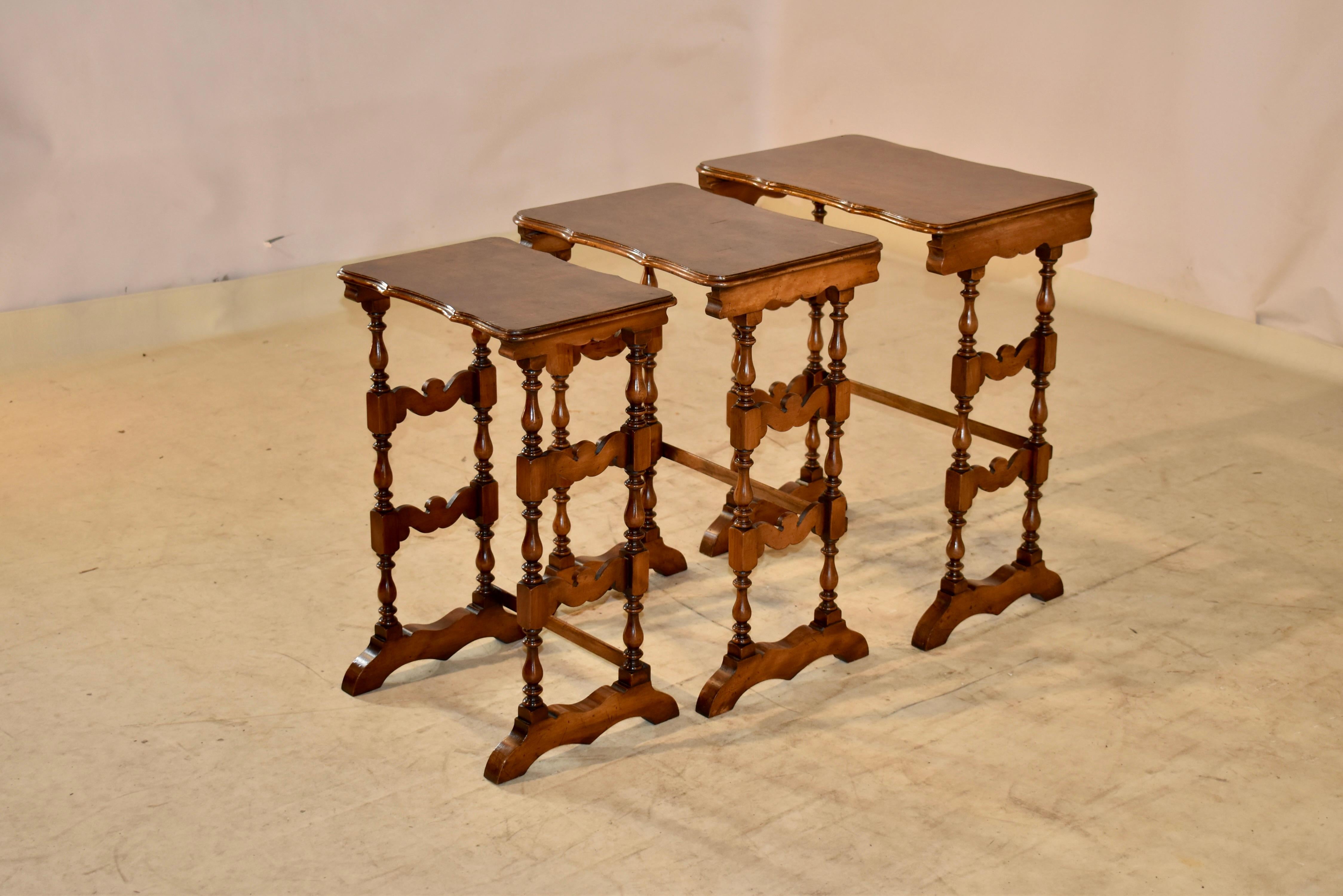 19th century set of three nesting side tables from England. The tables have burl walnut tops with scalloped and beveled edges on the front and back for added design detail. The tables are supported on trestle type legs with lovely hand scalloped