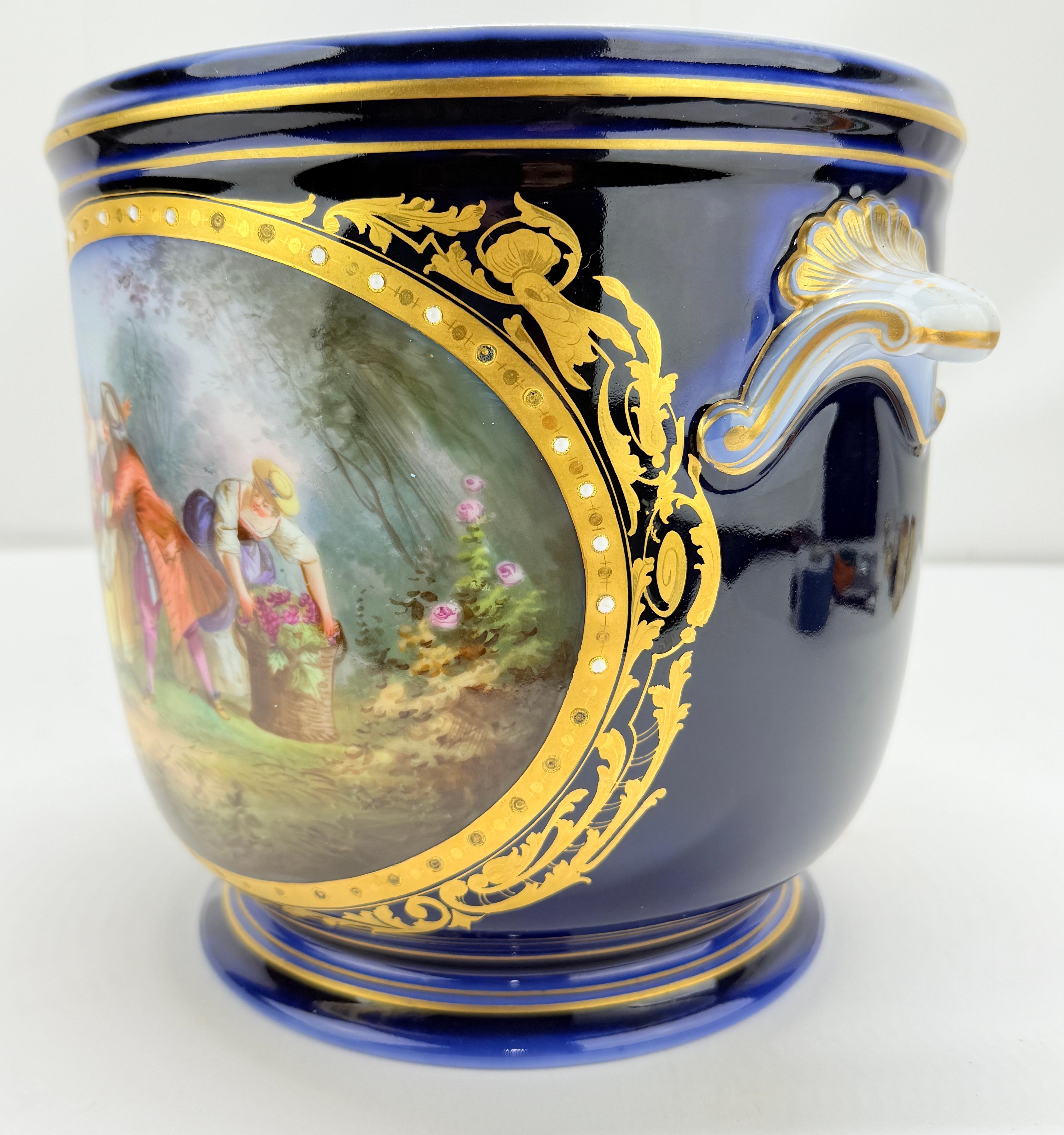 A fine and richly decorated French porcelain jardinière by the Sèvres manufactory, dating to the late 19th or early 20th century, distinguished by its opulent cobalt blue ground and hand-painted reserves in the 18th-century taste. The principal