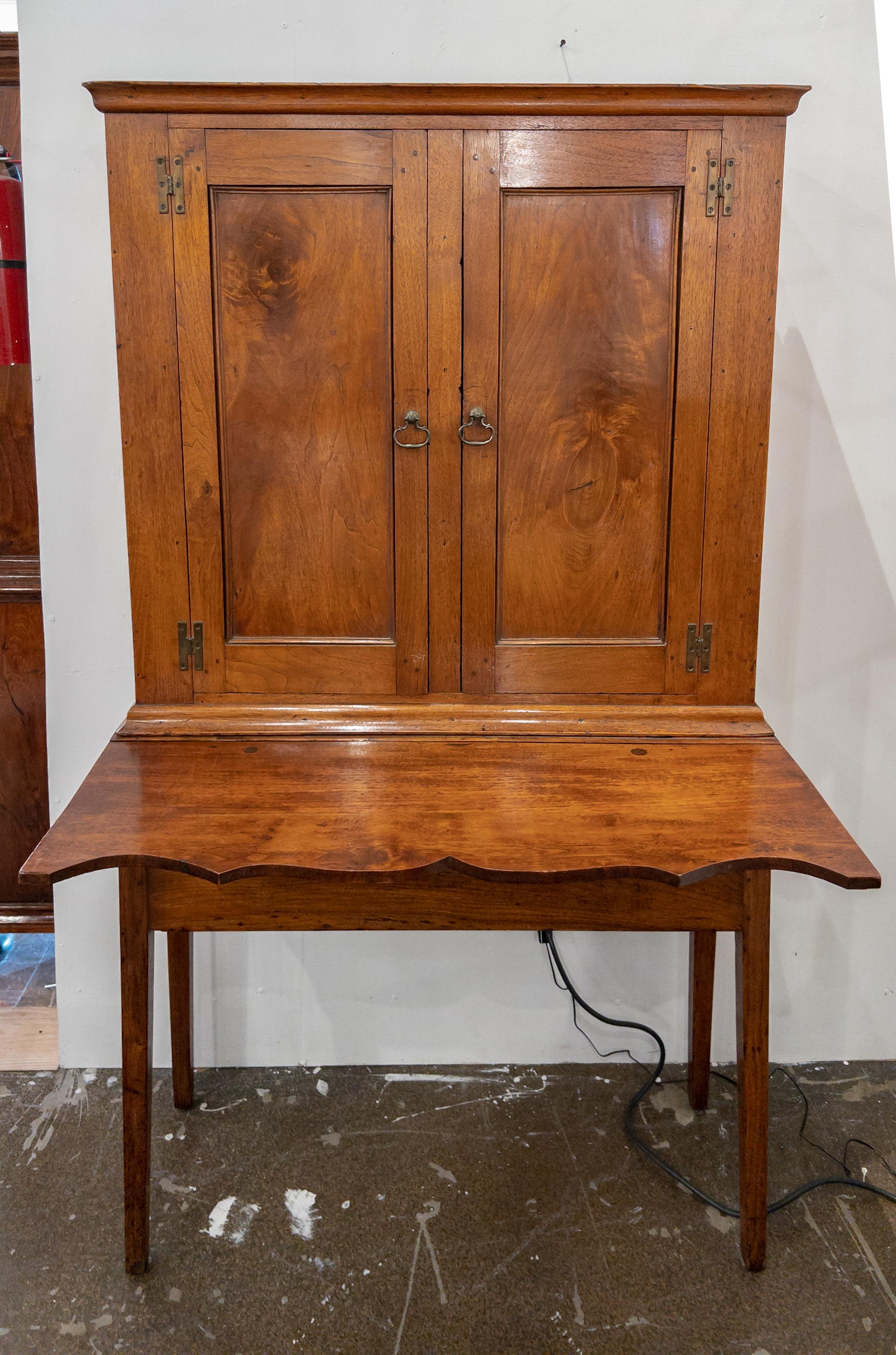 19th Century Shaker Style cabinet on legs with a pull up writing surface. The cabinet has two upper block panel doors and three shelves in the interior. There is also a drawer underneath the writing surface.