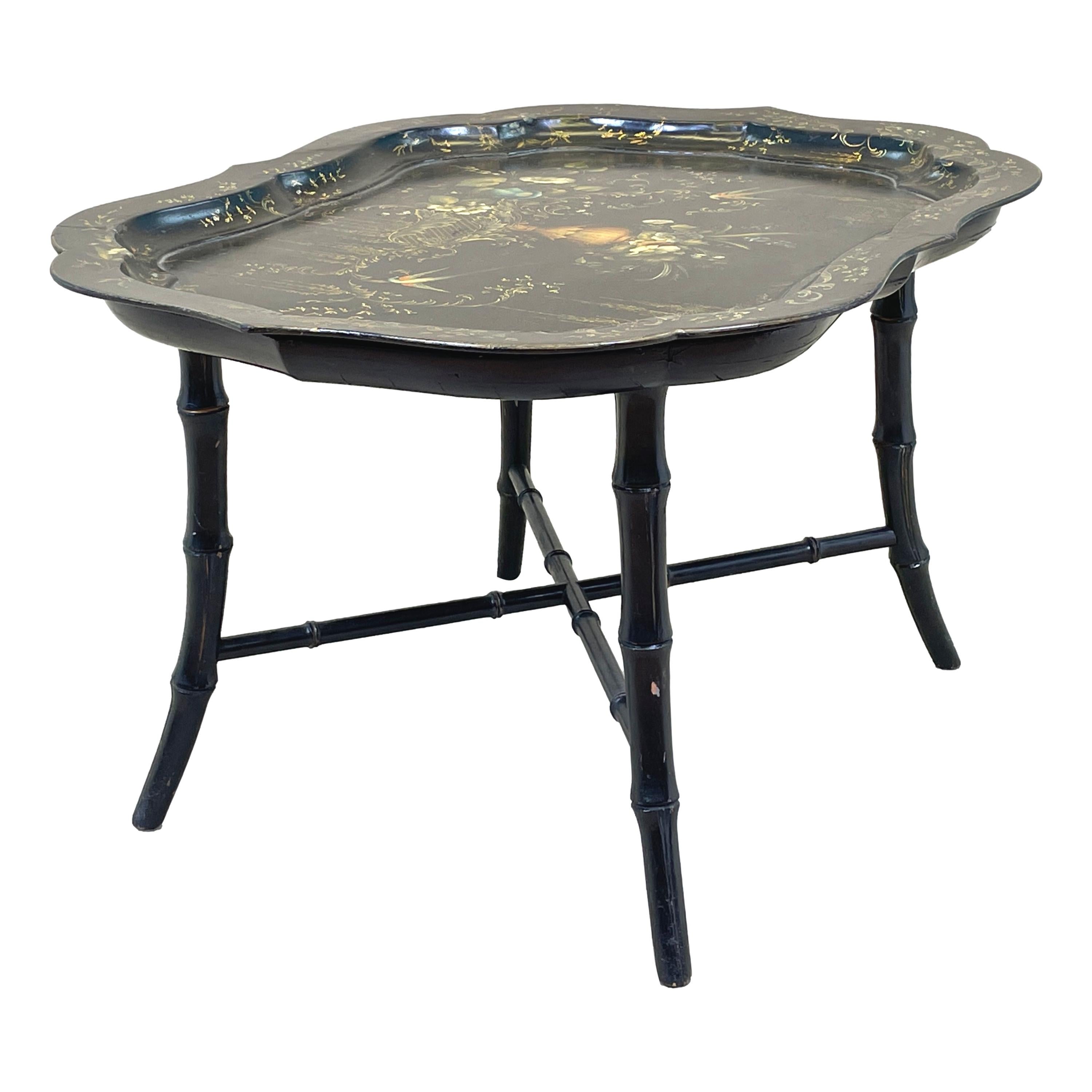 A very good quality mid 19th century papier mache tray on stand, or coffee table, having extremely attractive hand painted and gilded decoration to try top with elegant shaped edge, raised on later bamboo effect tapered leg stand.

What better way