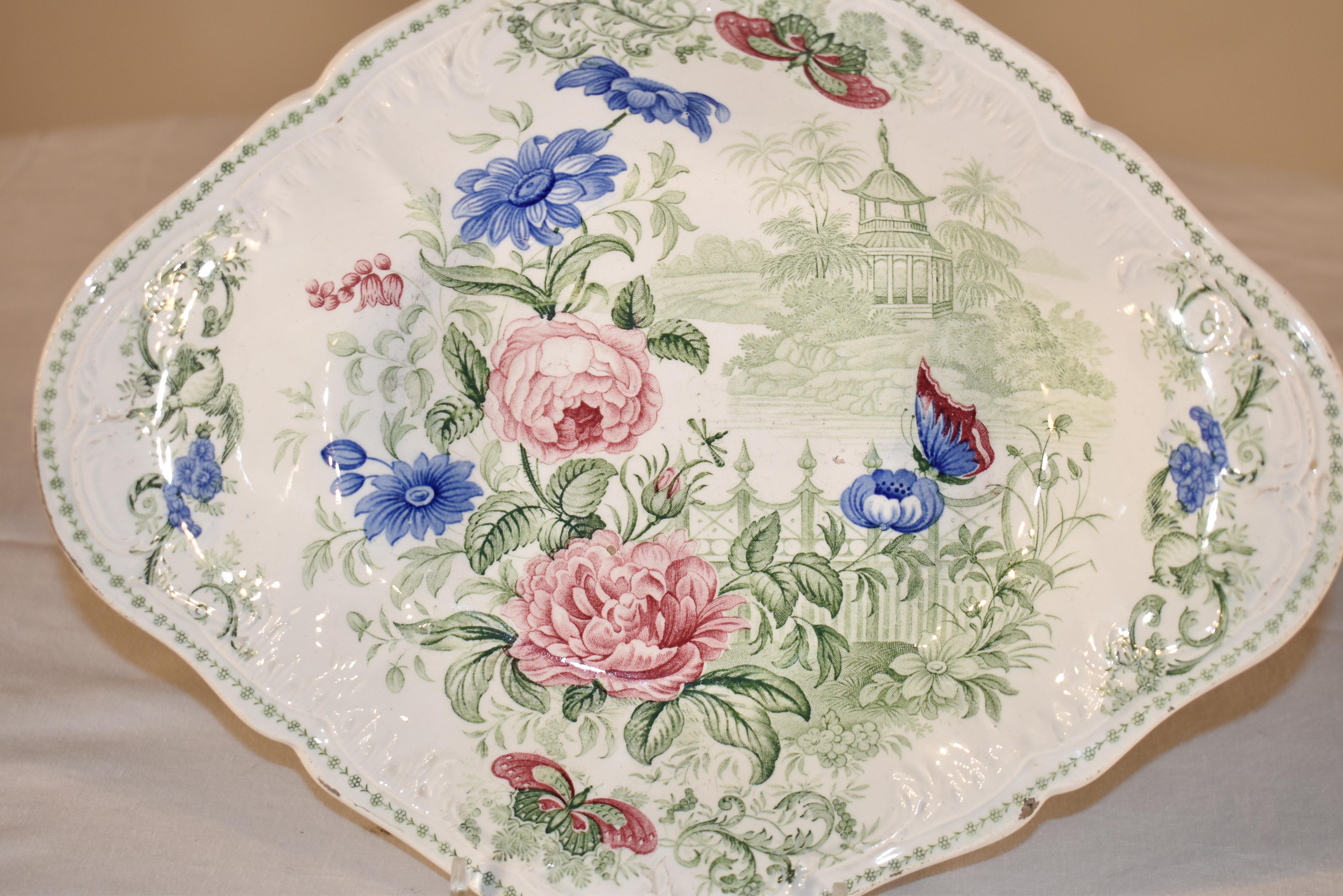 19th century shaped serving dish with multicolored transfer decoration depicting a garden with florals and butterflies in vibrant color. Marked 