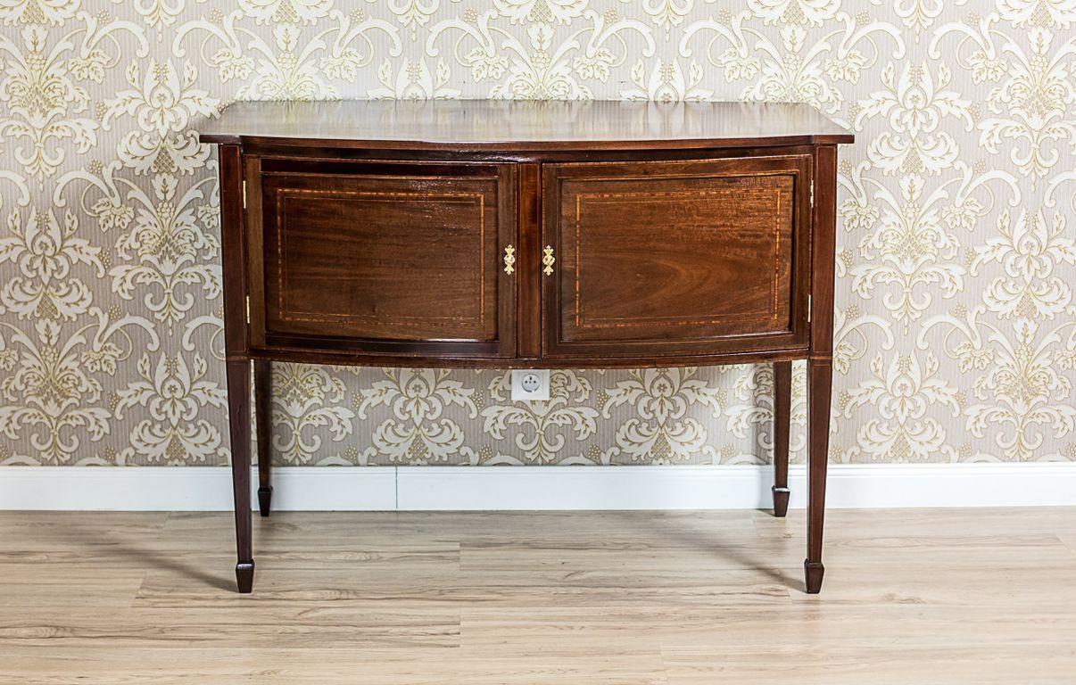 19th-Century Sheraton Cabinet in Brown Veneered with Mahogany

We present you this 19th-century piece of furniture in the type of a cabinet or a commode, veneered with mahogany.
The two-door chasing section is rounded from the front.
Moreover, it is
