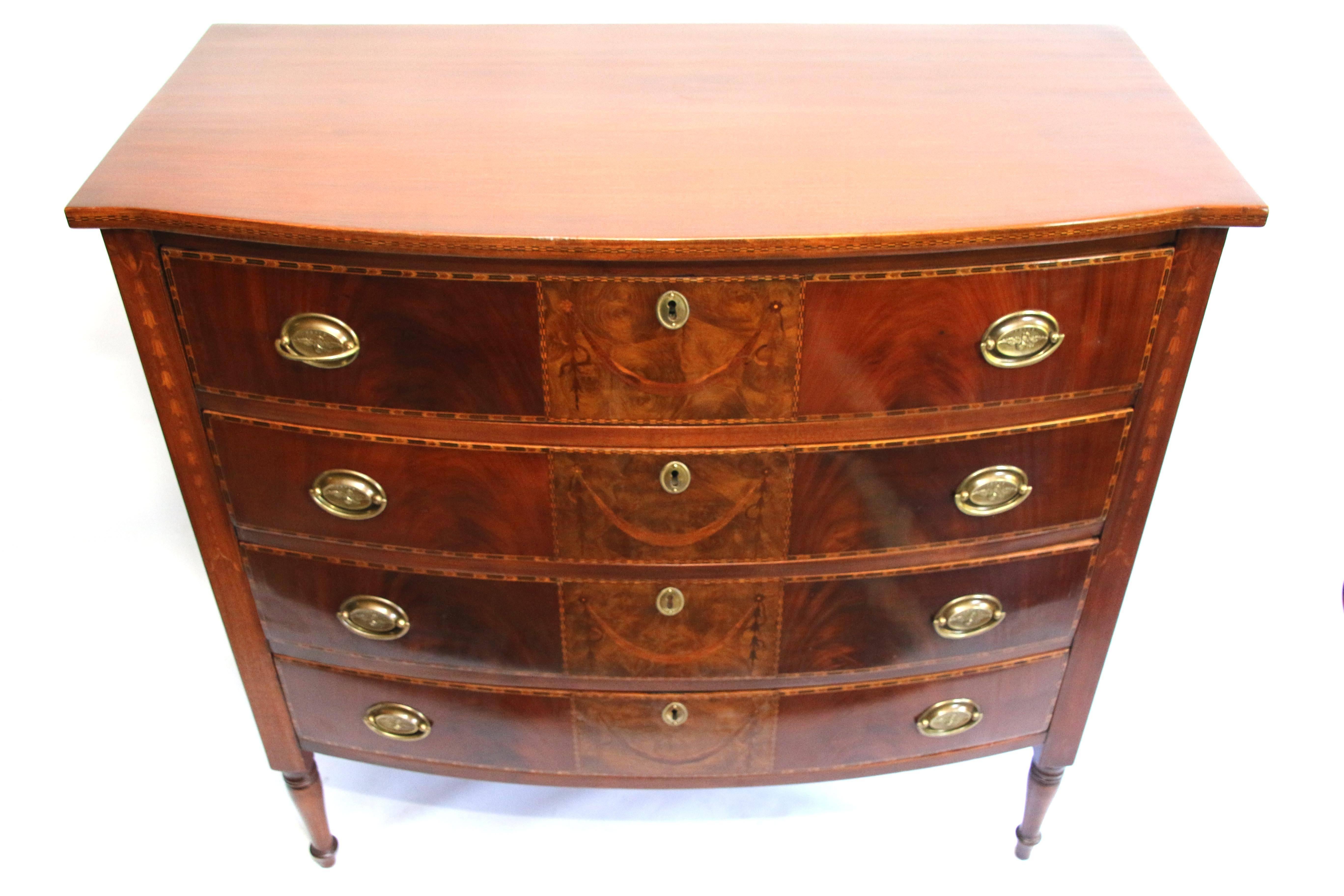 Fine Sheraton four-drawer inlaid bowfront chest having a shaped top with checkered inlaid banding over four full drawers, each having fronts centring on inlaid panels with swag rosette and bellflower inlay. Flanked by burled wood panels. Framed with