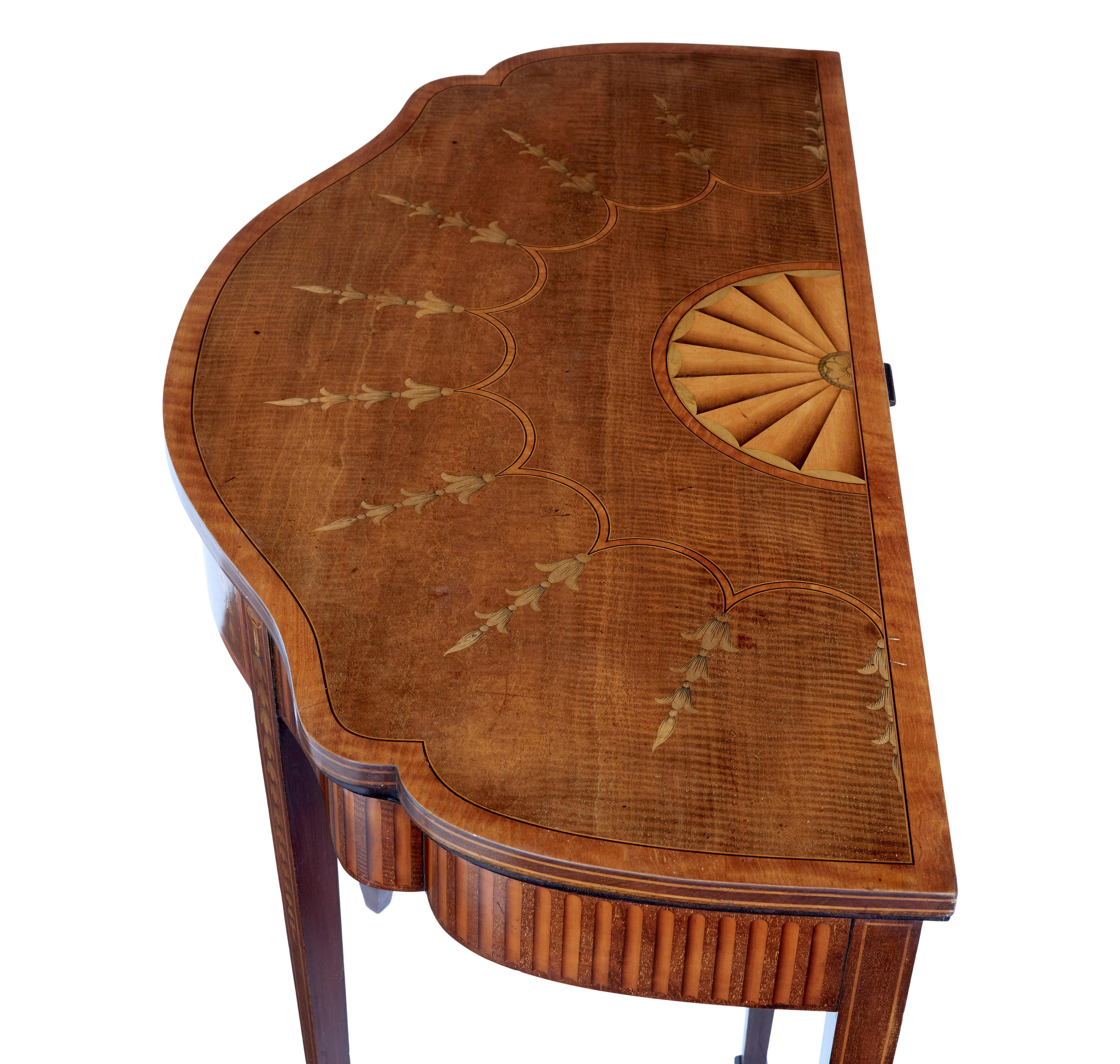 19th century Sheraton revival inlaid mahogany card table, circa 1880.

Shaped carved victorian carved card table in the sheraton revival style. Inlaid with a fan and florals in satinwood. Finished with stringing. Back leg pulls out to provide