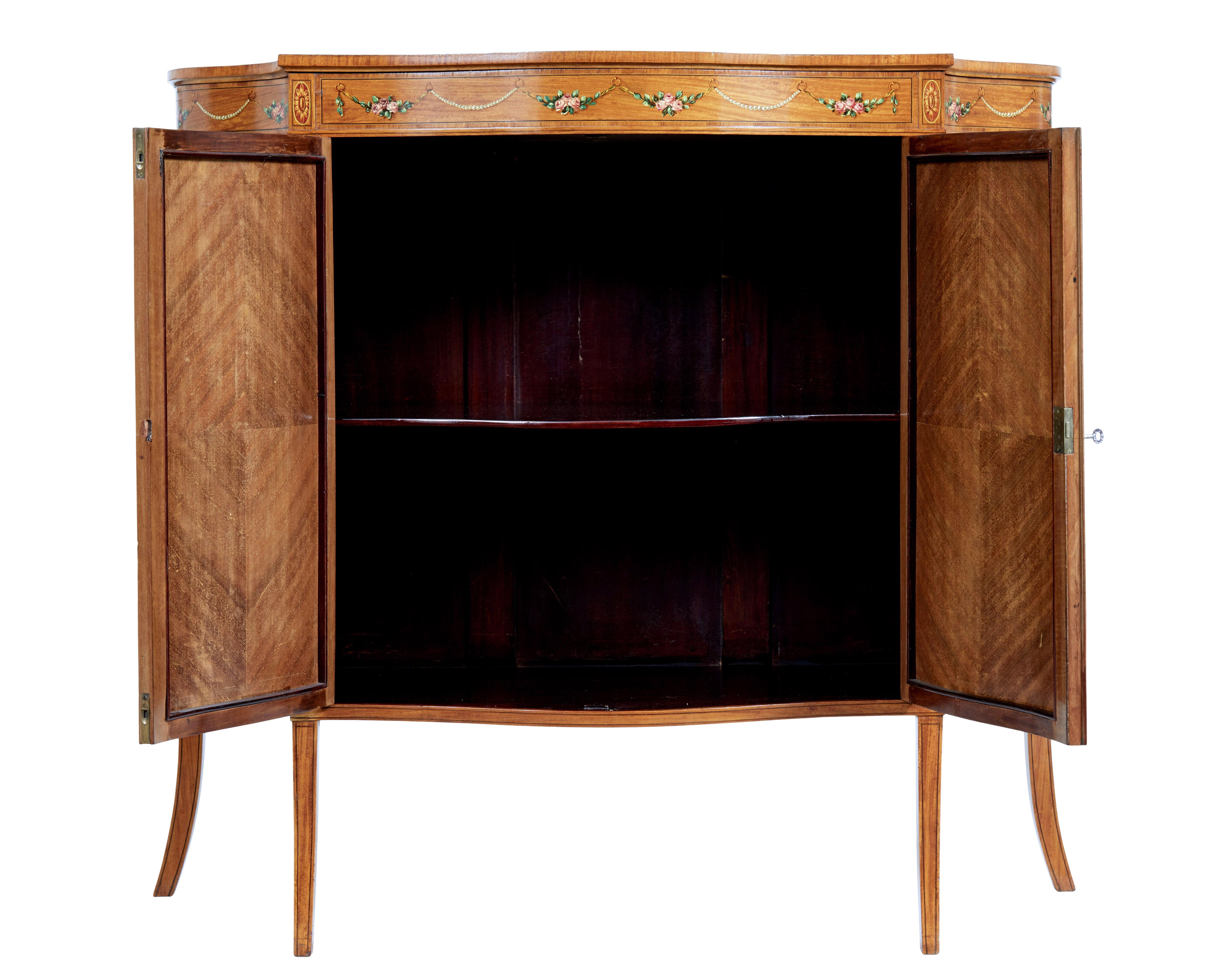 Armadio Sheraton Revival della fine del XIX secolo in legno satinato intarsiato e dipinto, circa 1895.

Splendido mobile a 2 ante con fronte a serpentina che poggia su 4 gambe affusolate. Sul davanti, 4 targhe dipinte a mano raffiguranti una natura