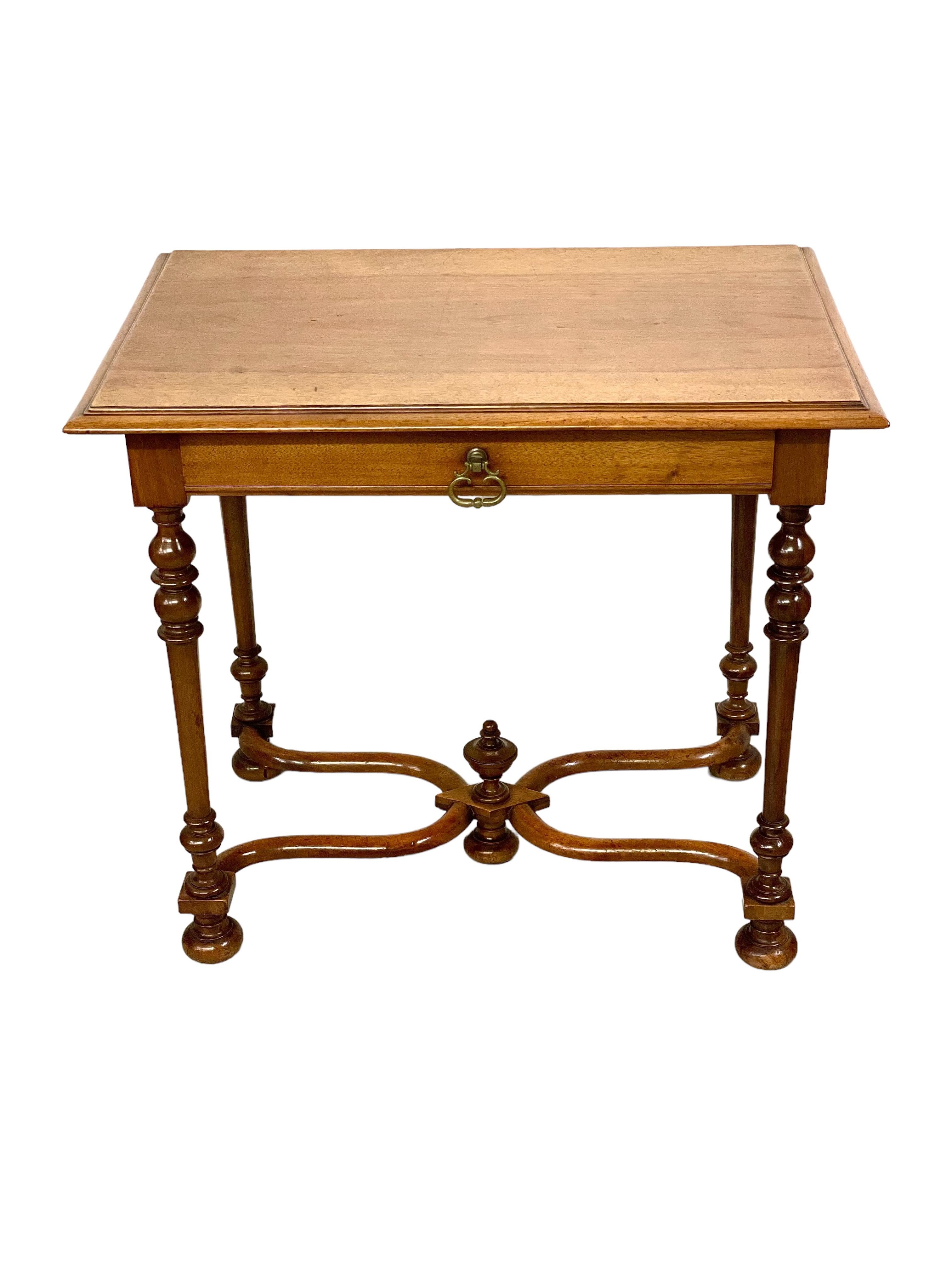 An absolutely charming 19th century Baroque style French side table, crafted from walnut and featuring exquisitely baluster turned and tapering legs, and a beautifully curved X-form stretcher with central urn finial. This petite desk has a polished,