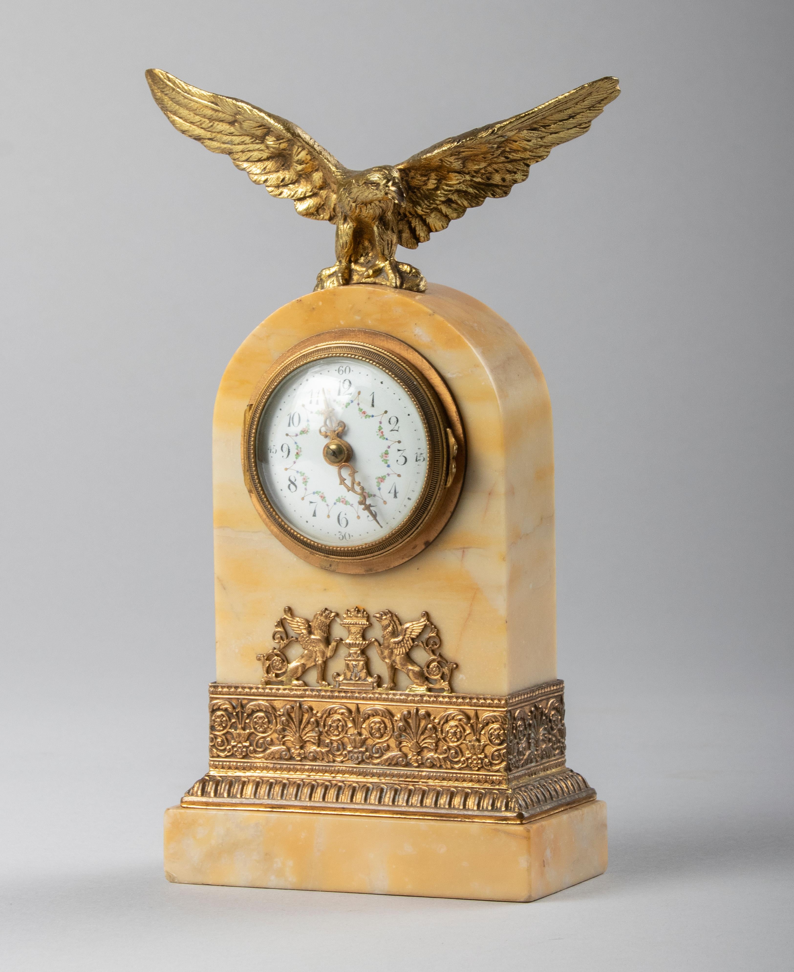 Am Empire style small travel clock. The case is made of Siena marble with on top an imperial bronze eagle which was the symbol of the first and second Empire period. The marble case all around embellished wit gilt copper. The enameled dial have hand