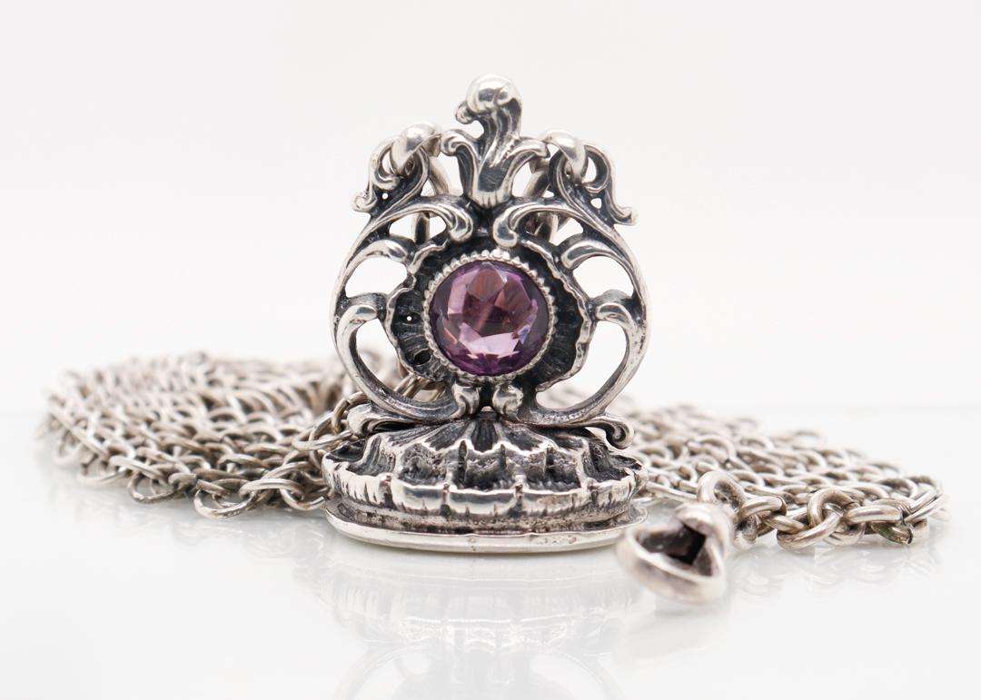 A very fine antique silver and amethyst watch fob & mesh watch chain.

With a round faceted amethyst gemstone bezel set center of rocaille watch fob. 

The fob is attached to a Victorian sterling silver mesh chain with a clasp.

A wonderful silver