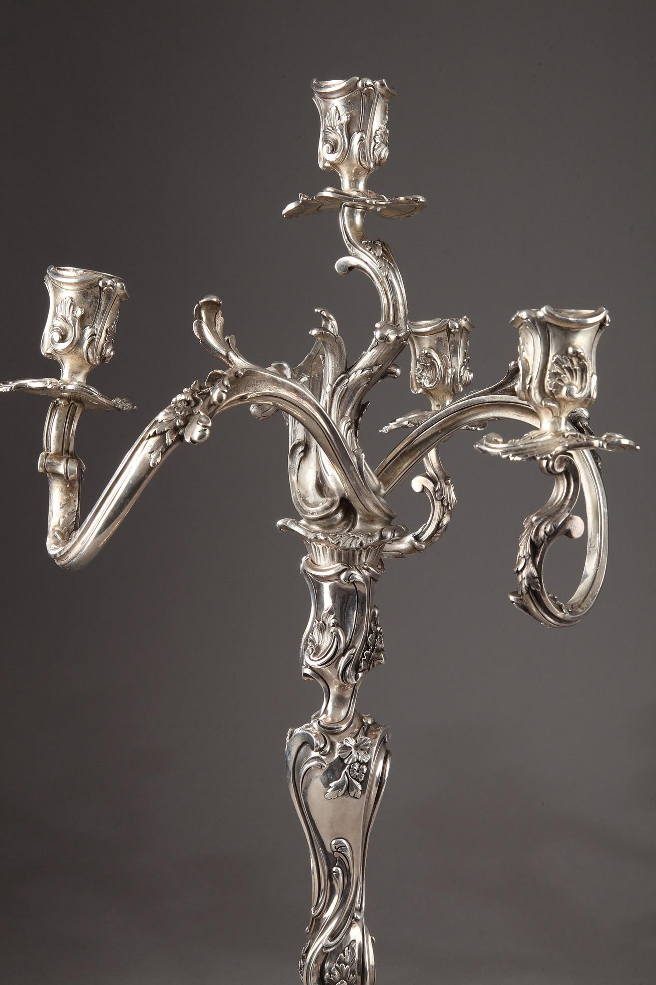 Pair of Louis XV style candelabra in silver with rocailles decor and asymmetrical ornamentation. The four arms of light ending in bobèches binettes are finely chiseled with stylized rinses, foliage and flowers.

These candelabra are a creation of