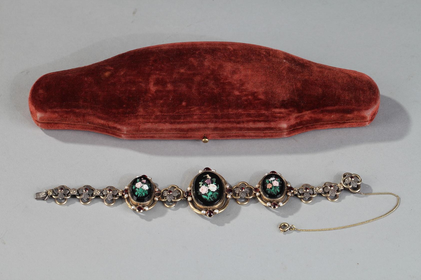 Bracelet en vermeil composé de trois médaillons décorés de micromosaïques sur fond d'onyx noir. Les micromosaïques représentent des bouquets de fleurs multicolores, et la monture est ornée de grenats et de perles. Les médaillons sont entrecoupés