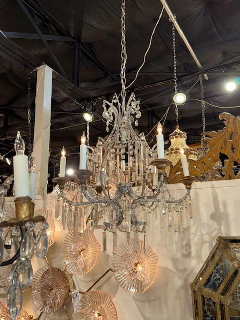 Questo lampadario del XIX secolo in legno dorato d'argento e prismi di cristallo presenta un design elegante con accenti in legno dorato d'argento e prismi di cristallo scintillanti. L'abbinamento di argento e cristallo crea un look lussuoso e senza