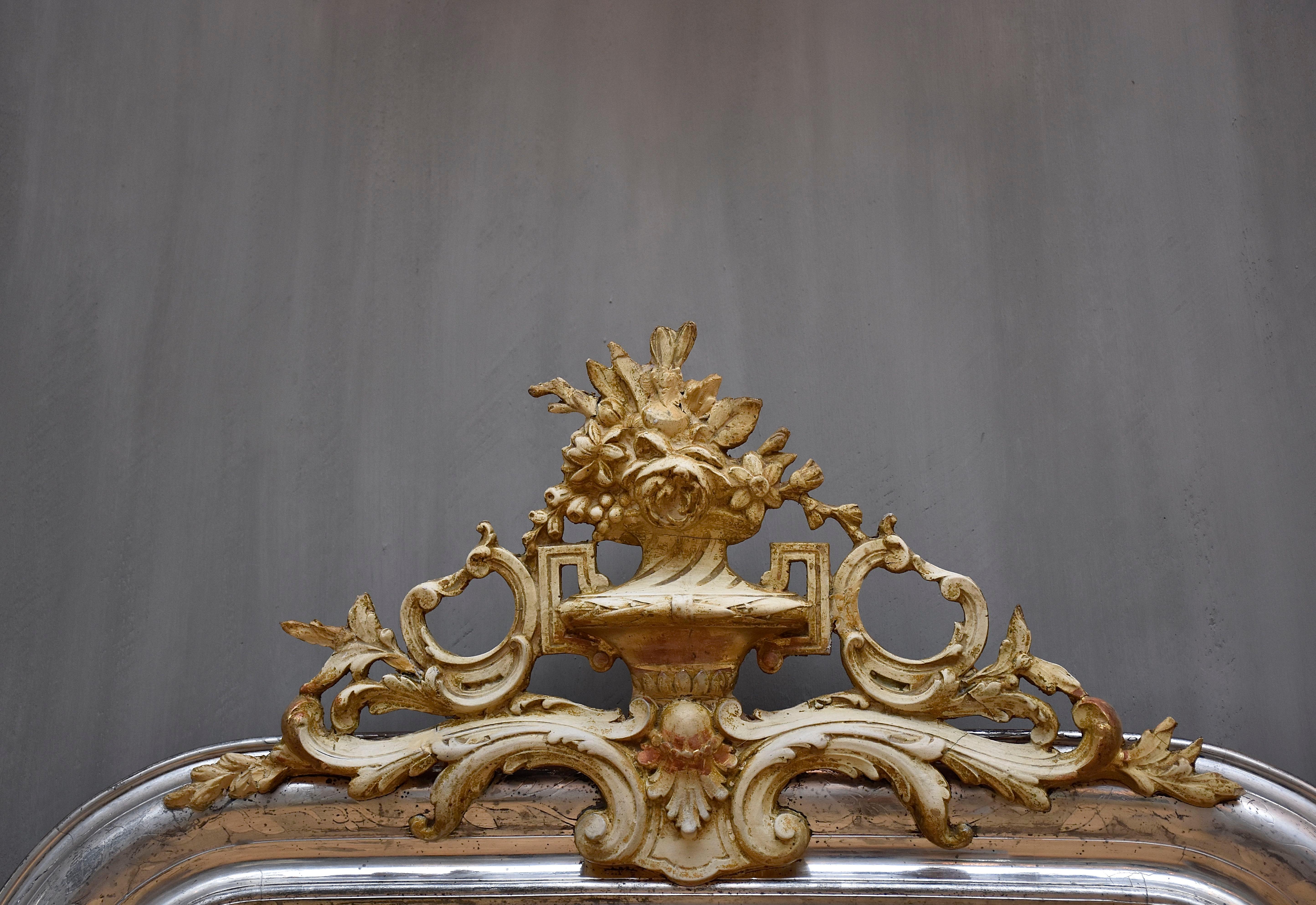 Ein hübscher antiker französischer Spiegel mit einem Wappen.
Das Wappen ist mit Blumen und Blättern verziert. 
Der Rahmen ist mit Blattsilber vergoldet und mit geätzten Blattmotiven versehen.
Das Glas ist antikes, silbernes Spiegelglas.
Herkunftsort