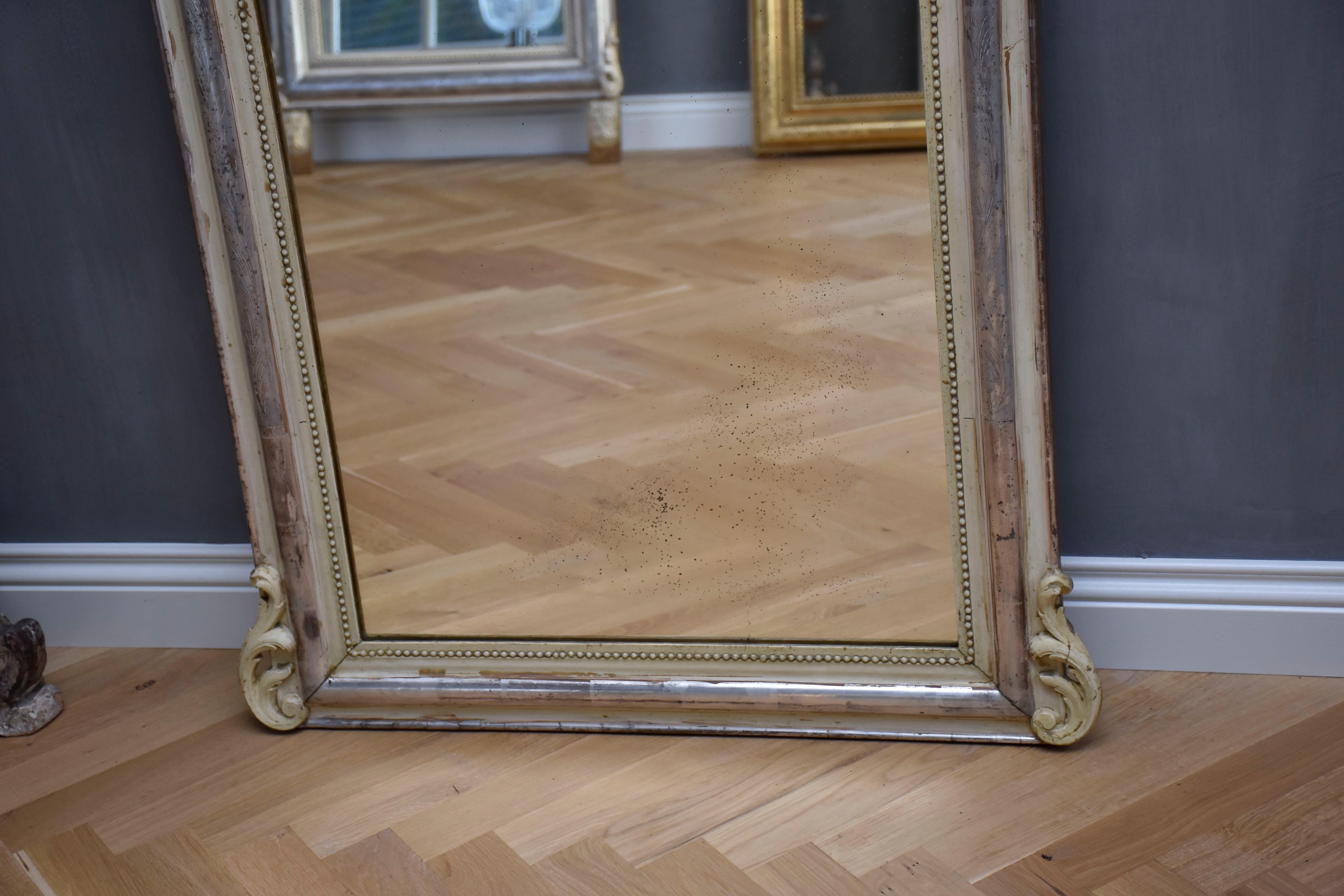 Very pretty 19th century French mirror with its original, slightly foxed antique glass and a beautiful open work crest.
The frame has an original silver-leaf gilding, is etched with leaves and has a beaded edge.
Below a corner ornaments.
The mirror