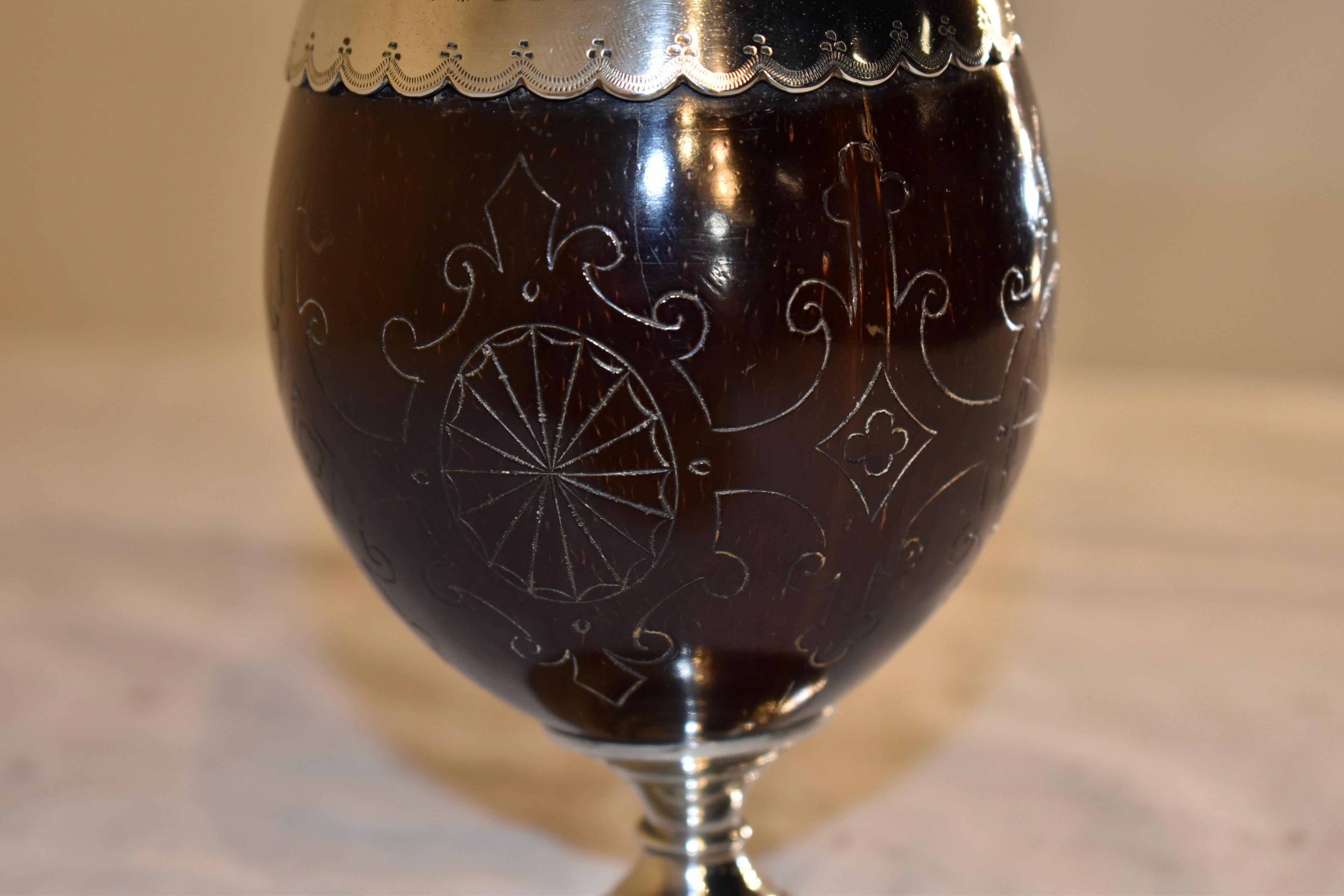 Early 19th century silver mounted coconut cup from England.  The cup itself is made from a coconut, which has been hand carved with geometric patterns, and worn smooth from age and use.  The interior of the cup is most likely silver-plated, with the