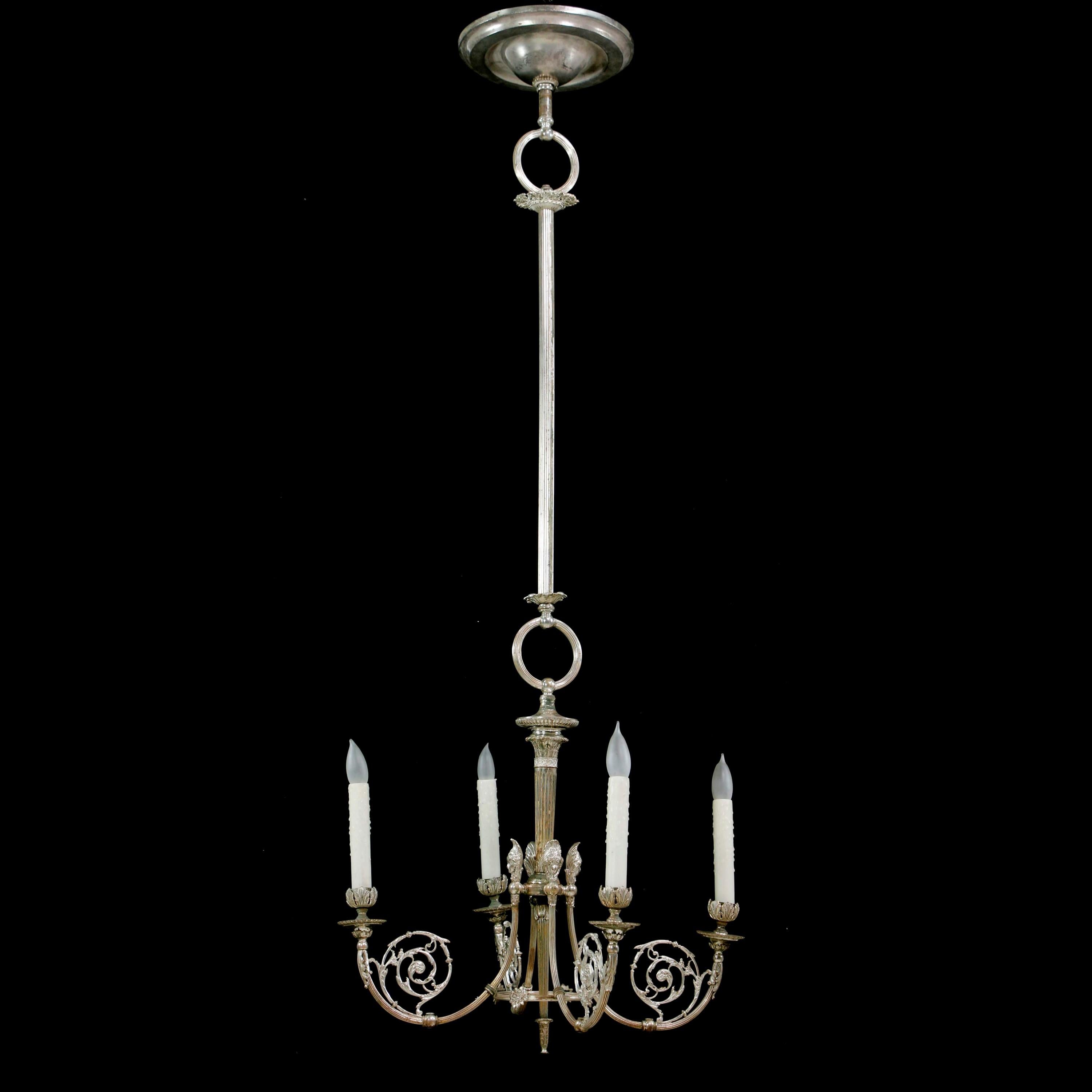 Questo delizioso lampadario in ottone argentato del XIX secolo era in origine un lampadario a gas. Presenta dettagli in filigrana e quattro teste di donna. Uno alla base di ogni candelabro. L'argento presenta un'usura naturale con riflessi in
