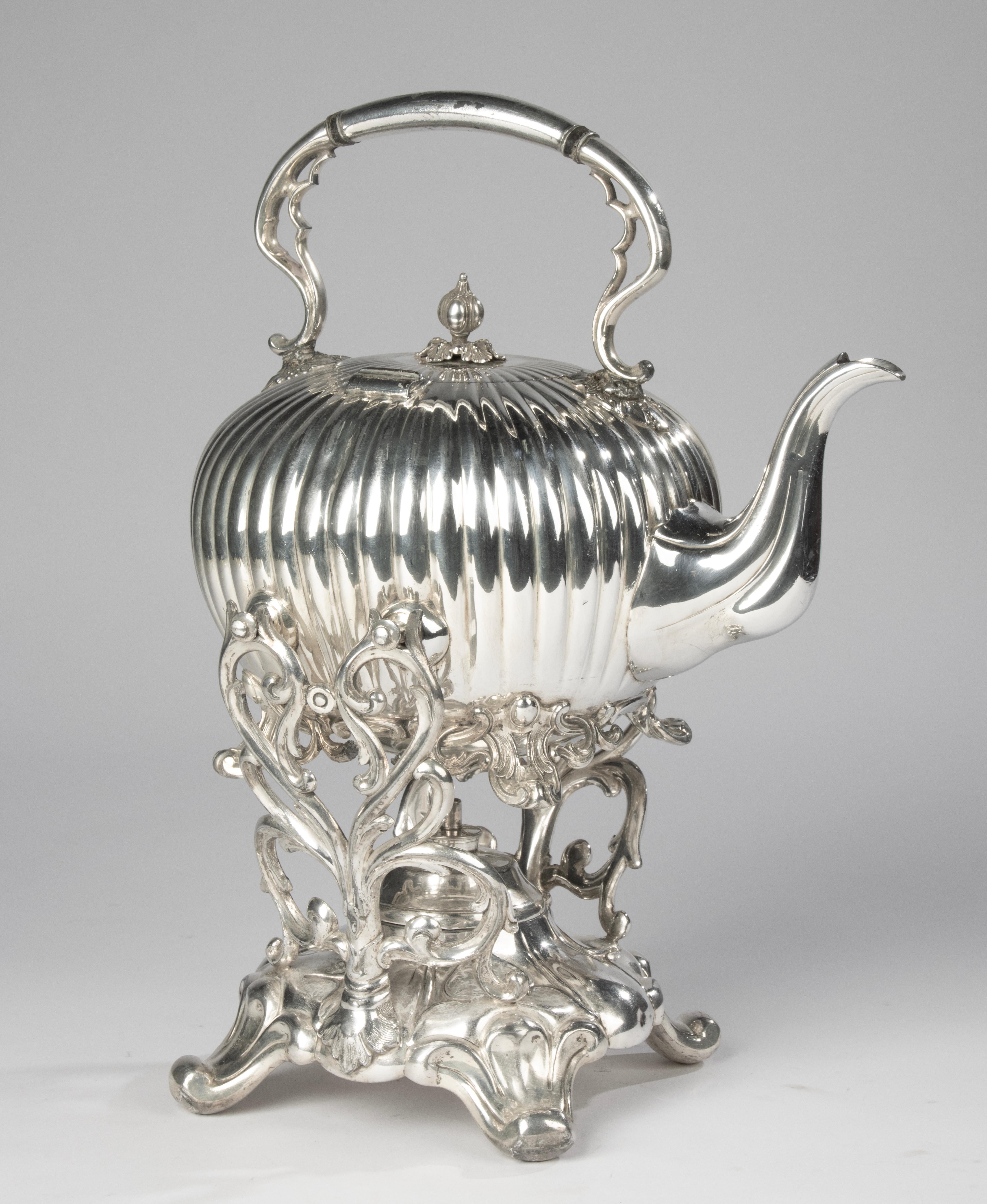 Una bellissima teiera antica su supporto, realizzata dal marchio inglese James Dixon & Sons, Sheffield.
La teiera a bollitore risale al 1870-1880 circa.
È in buone condizioni, con lievi segni dell'età. In alcuni punti lo strato d'argento è