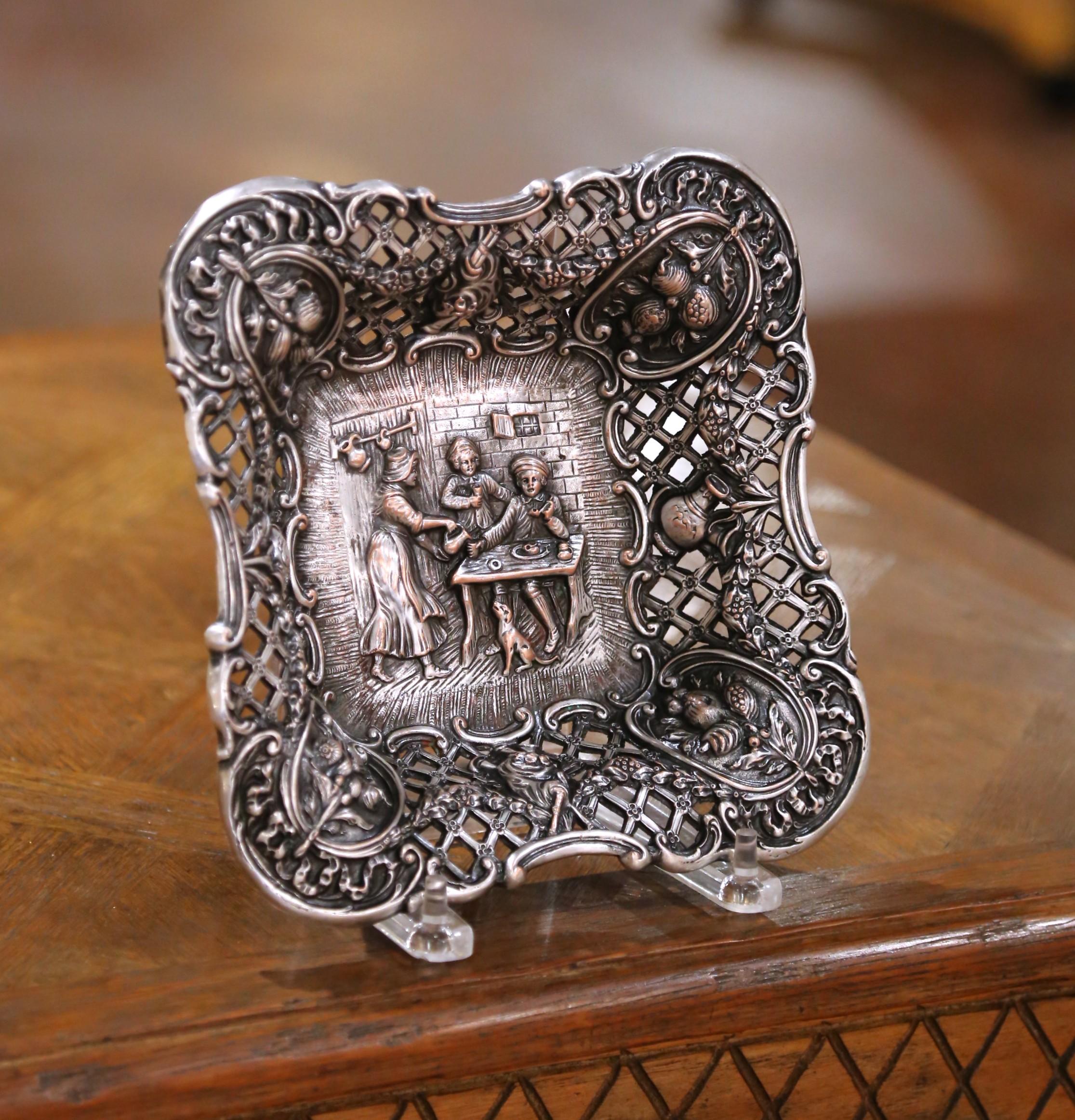 Realizzata nel Connecticut intorno al 1920 dalla Barbour Silver Company, questa ciotola finemente dettagliata è realizzata in rame argentato con un ricco lavoro di repoussé e trafori. La forma quadrata e smerlata è caratterizzata da un bordo aperto