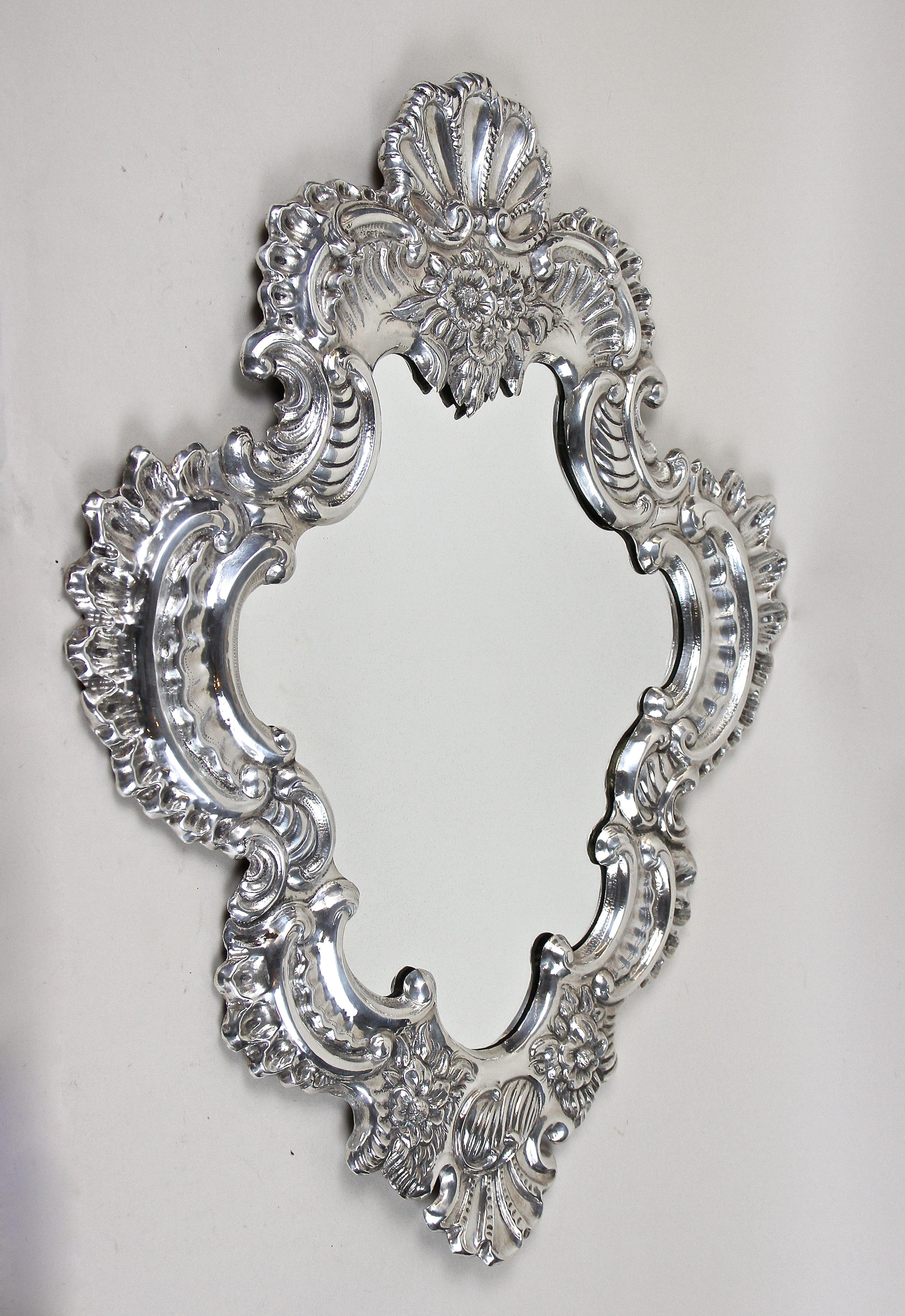 Excepcional espejo de pared italiano plateado de finales del siglo XIX, procedente de la isla de Venecia hacia 1890. Este espejo de elaborada factura impresiona con un marco de formas absolutamente artísticas hecho de cobre bellamente plateado. Este