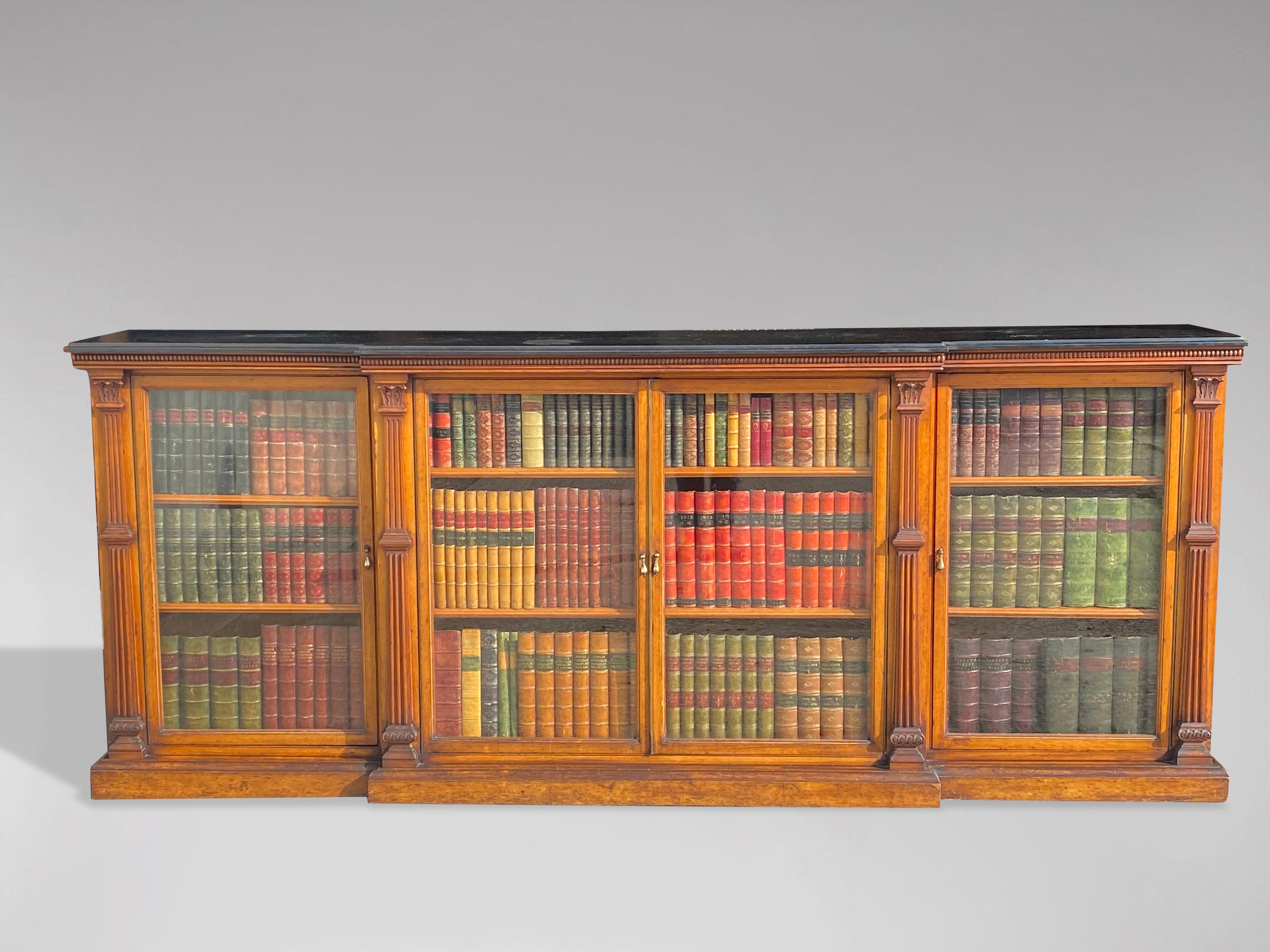 A large mid 19th century, early Victorian period solid oak breakfront library bookcase. Moulded slate breakfront top above four glazed doors. Each section has two adjustable shelves, providing substantial display space for books, flanked by six