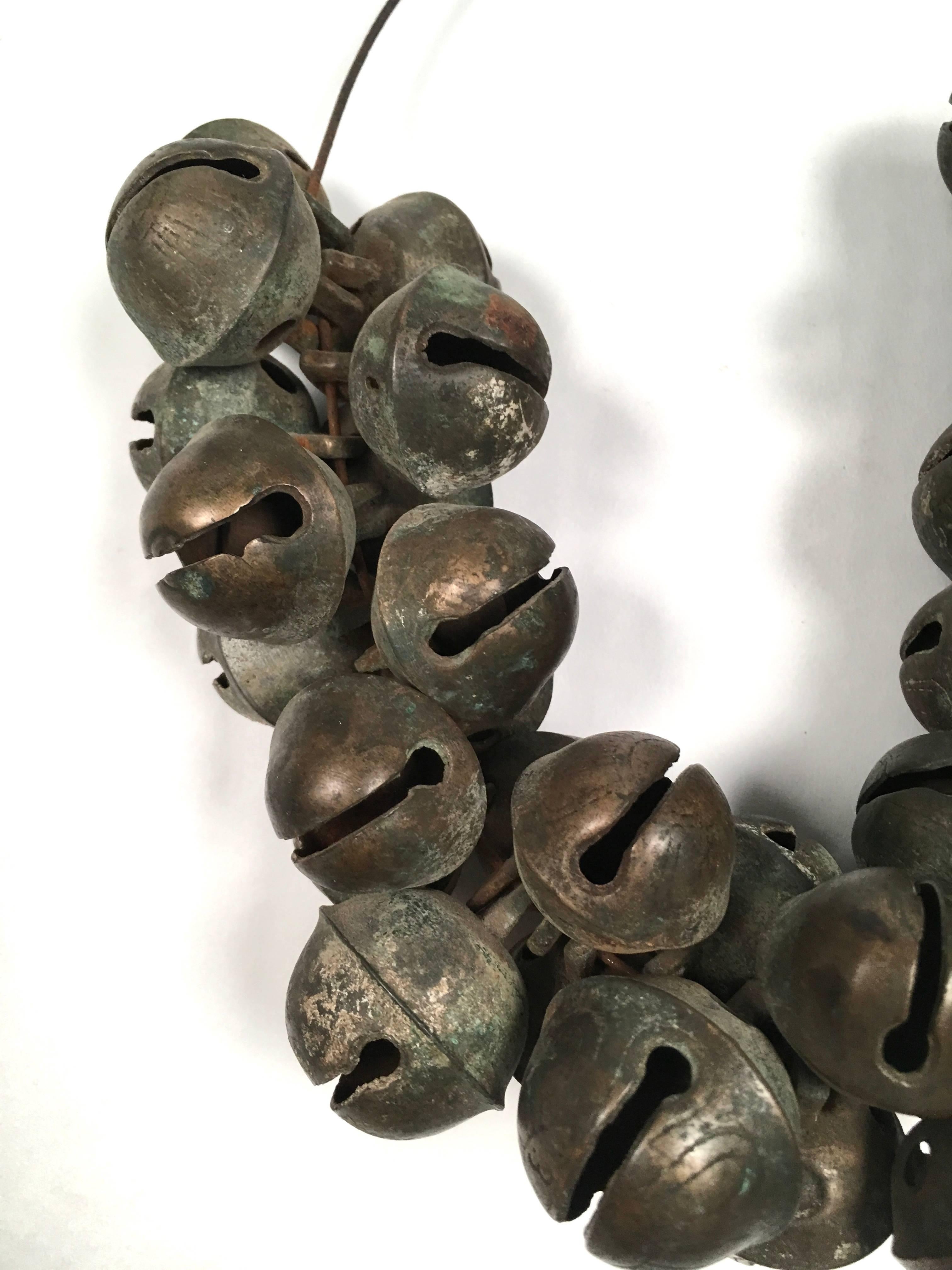 A large collection of 36 antique brass sleigh bells, which have a wonderful tone, in several sizes, engraved with a petal design and various numbers on a bent wire, as found. We wish we could attach a recording of the wonderful, perfect jingling