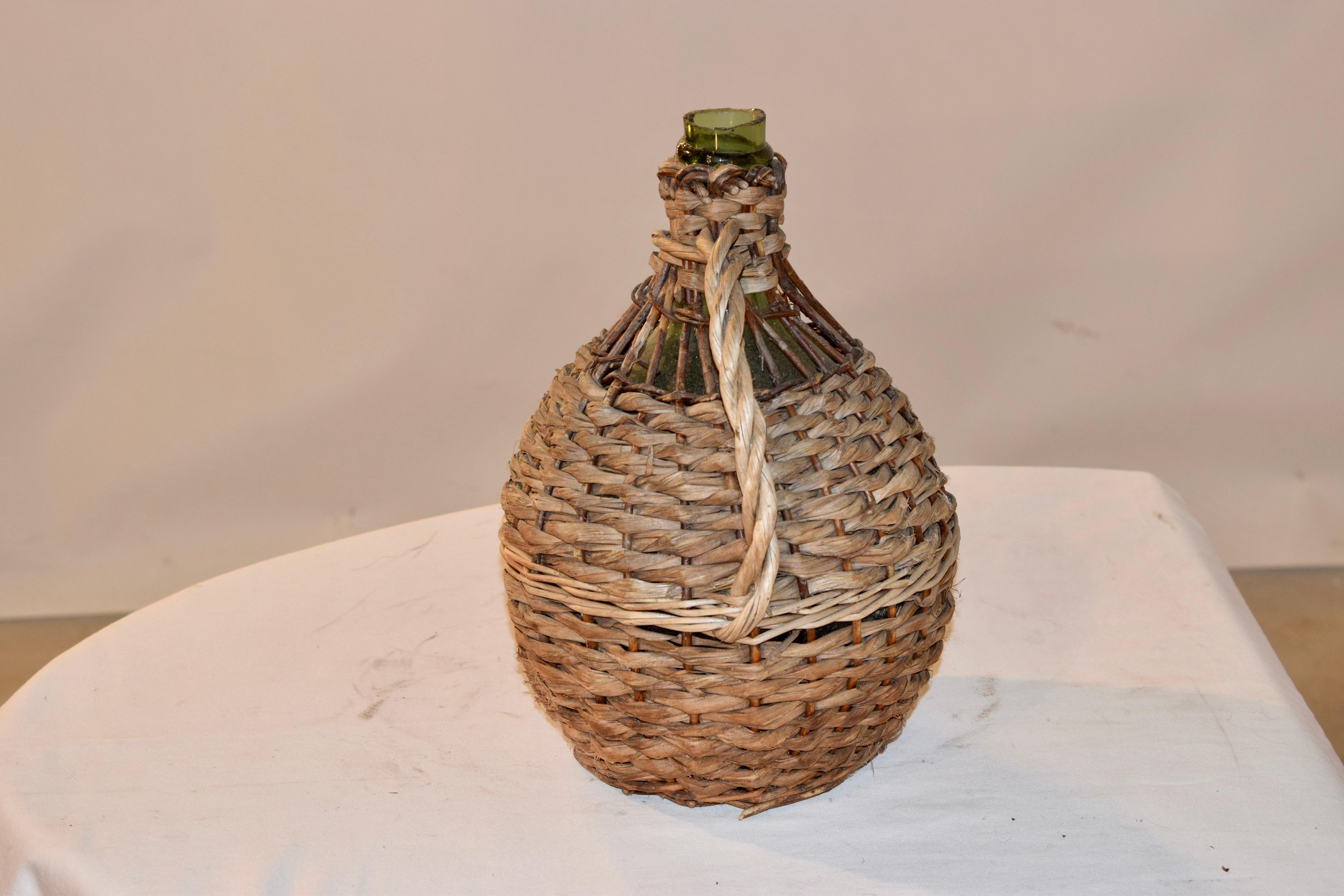 A small 19th century French globular form hand blown green glass demijohn bottle encased in original wicker frame and hand braided rope. The layers of rope and wicker create an interesting texture. A wonderful sculptural object with beautiful old