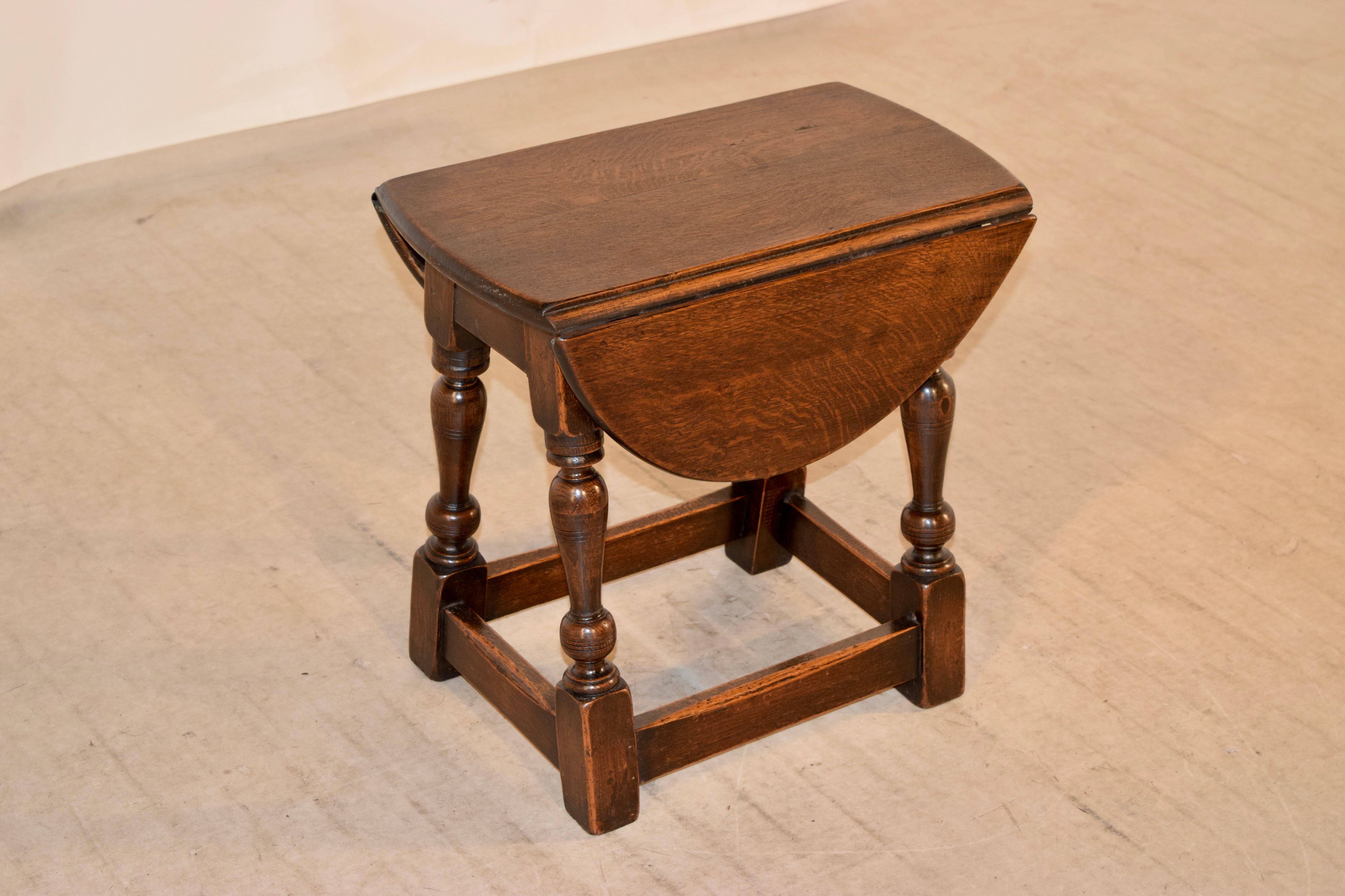 19th century small drop-leaf table from England made from oak. The top opens and turns to measure 25.25 x 19 inches. The top is supported on a base which has a simple apron and gently splayed turned legs, joined by simple stretchers.