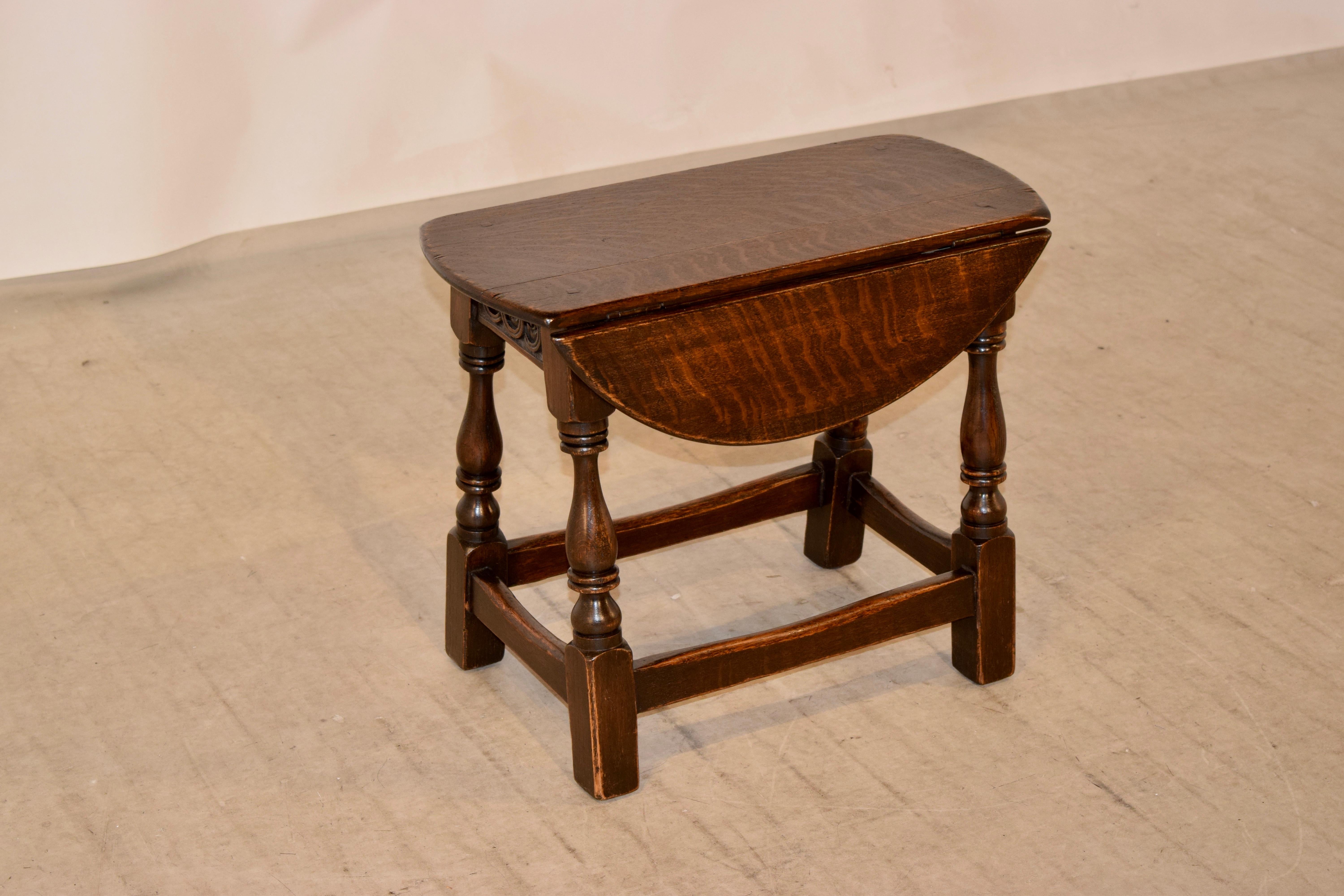 19th century small drop-leaf table from England with a wonderfully grained top and a simple apron with hand carved decoration on the ends, supported on splayed hand-turned legs joined by simple stretchers. The top when open measures 22 x 21.88.