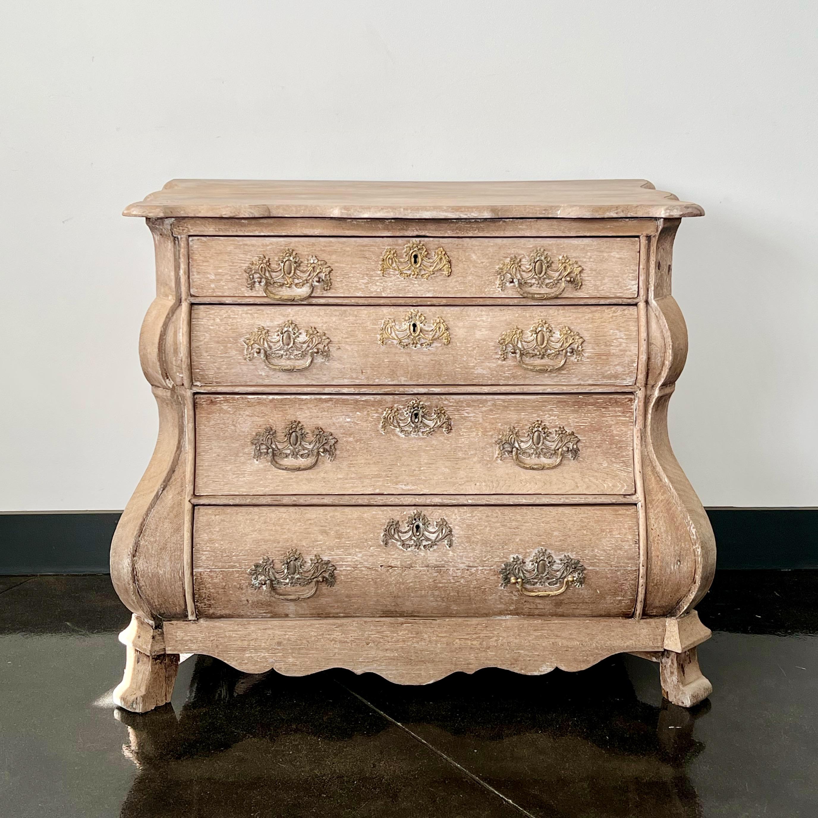 A charming four drawer small bombe front Dutch commode in bleached oak with original handsome bronze hardwares. 
Holland, circa 1860. 
More than ever, we selected the best, the rarest, the unusual, the spectacular, the most charming what makes
