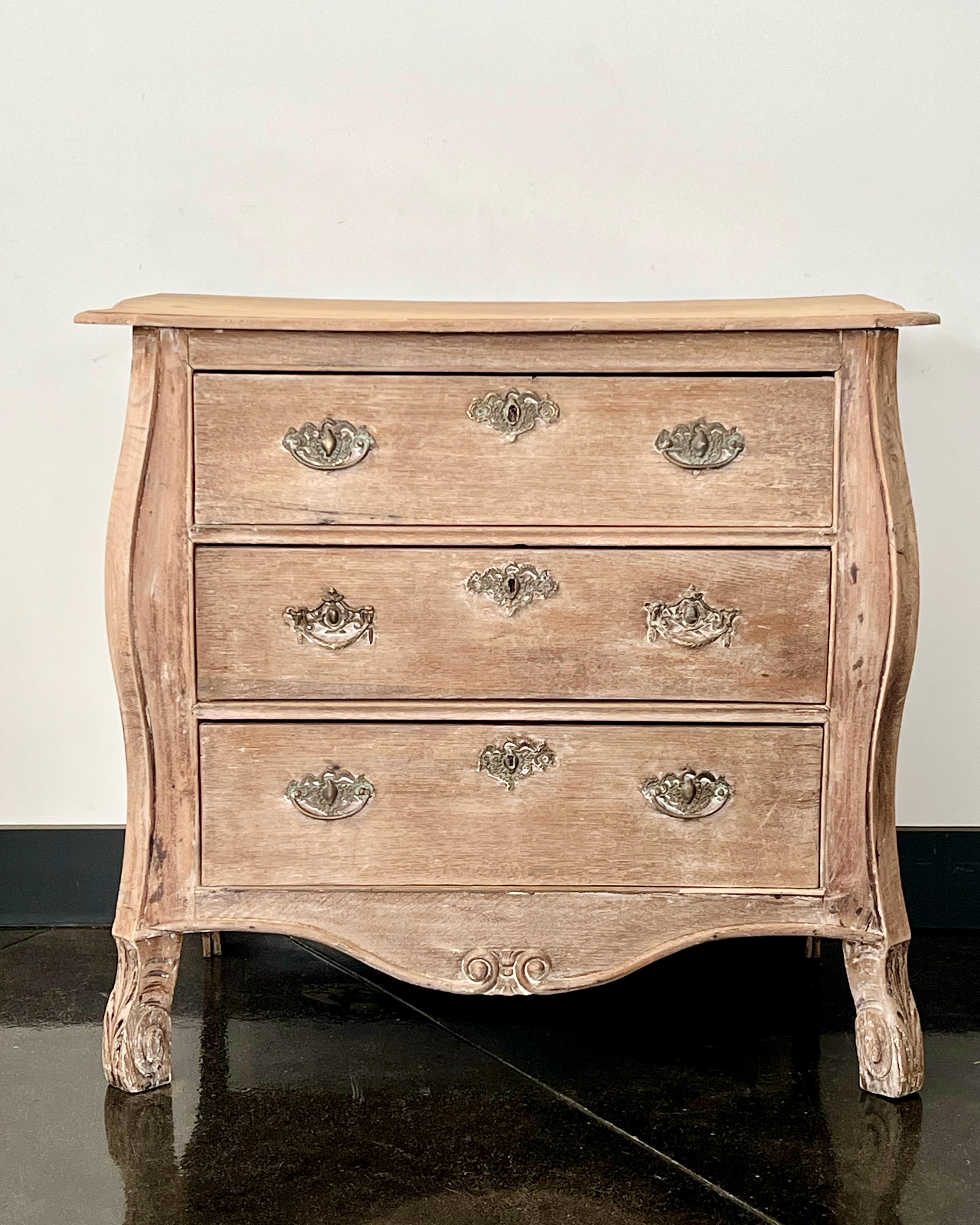 A charming three drawer small bombe front Dutch commode in bleached oak with original handsome bronze hardwares. 
Holland, circa 1860. 
More than ever, we selected the best, the rarest, the unusual, the spectacular, the most charming what makes