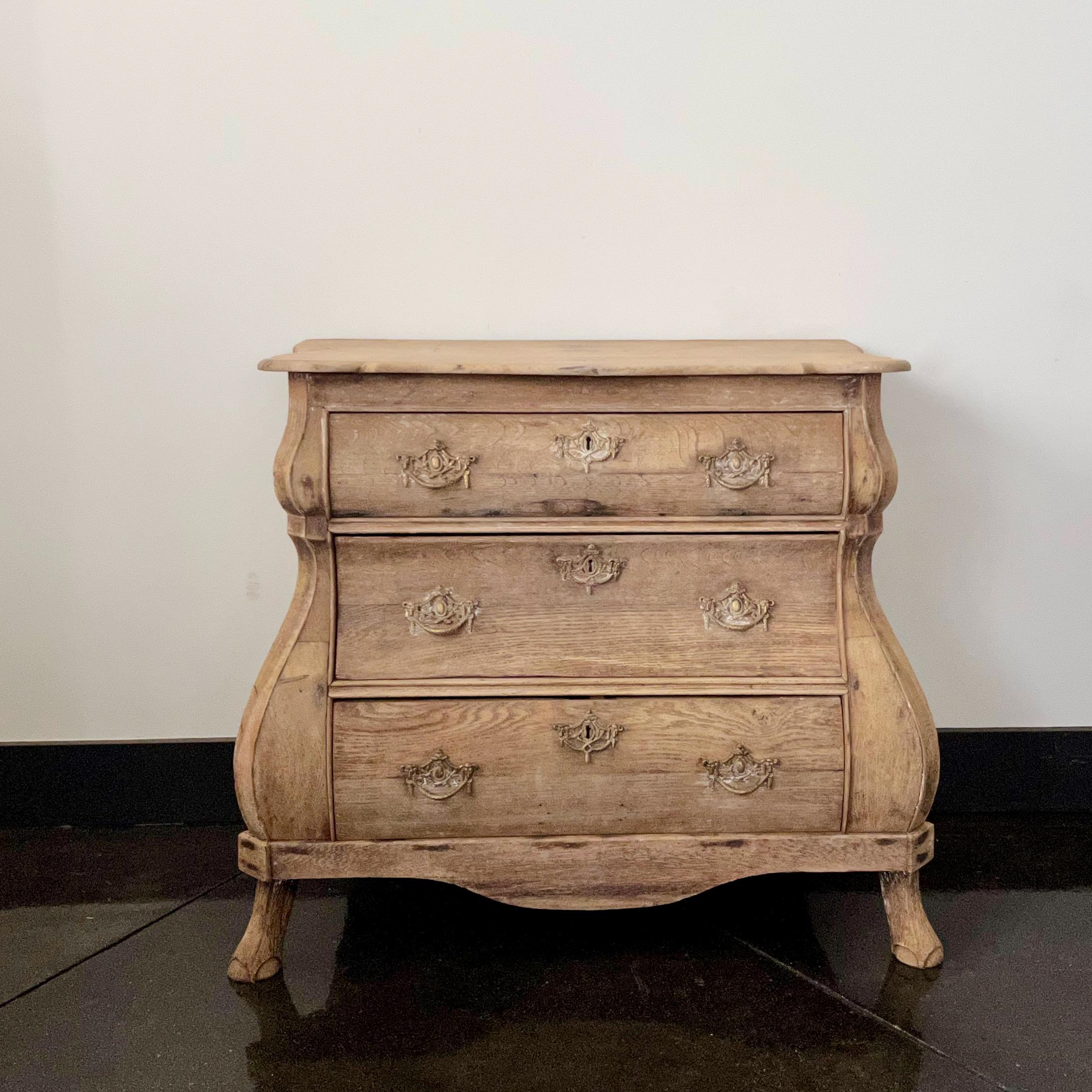 A charming three drawer small bombe front Dutch commode in bleached oak with original handsome bronze hardwares. 
Holland, circa 1860. 
More than ever, we selected the best, the rarest, the unusual, the spectacular, the most charming what makes