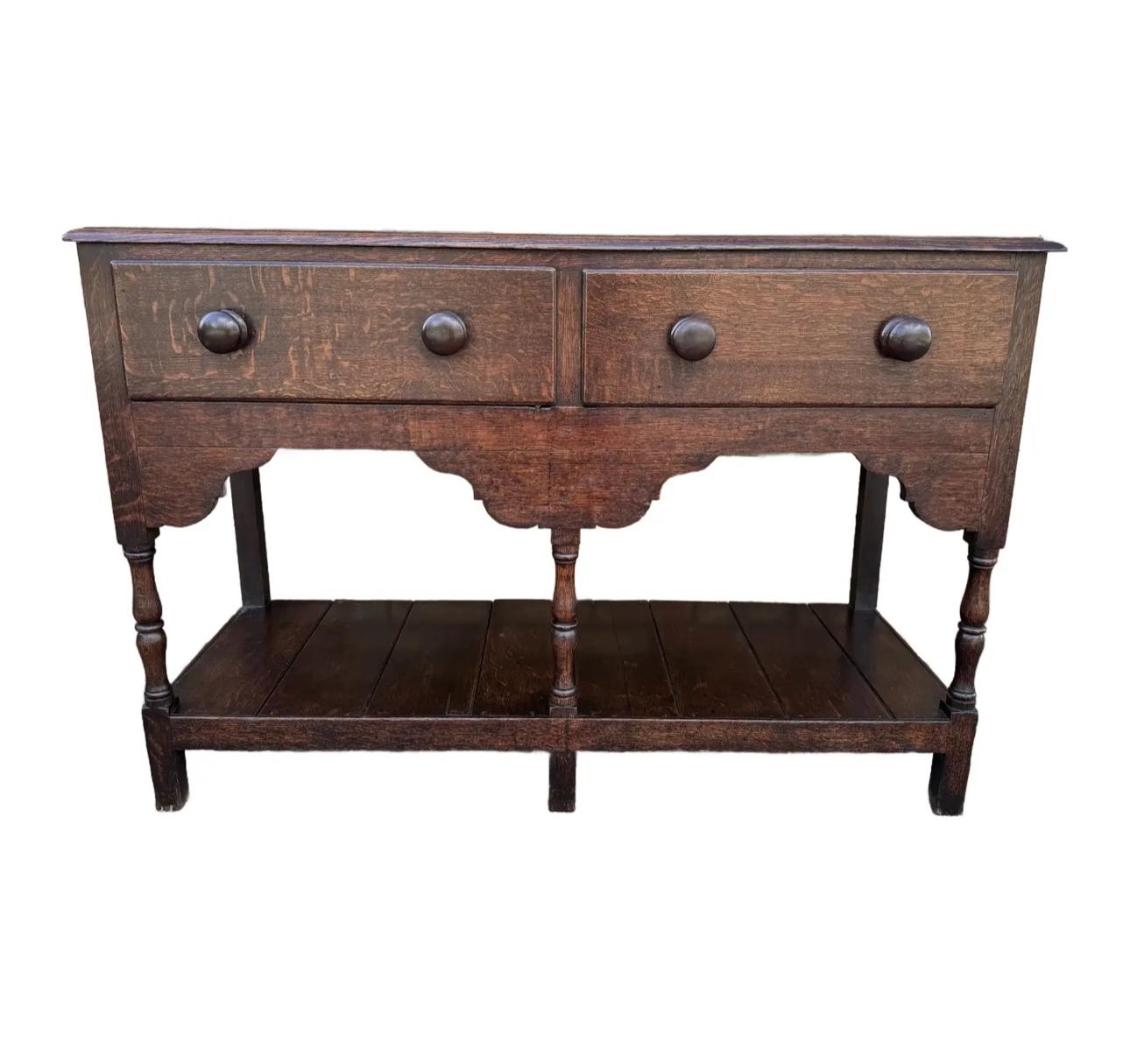 Il s'agit d'une base de commode anglaise de petite taille avec une planche à pot inférieure. Il possède trois pieds tournés sur la face avant avec des arcs de tablier joliment formés entre eux. Les 2 tiroirs coulissent bien grâce aux poignées en