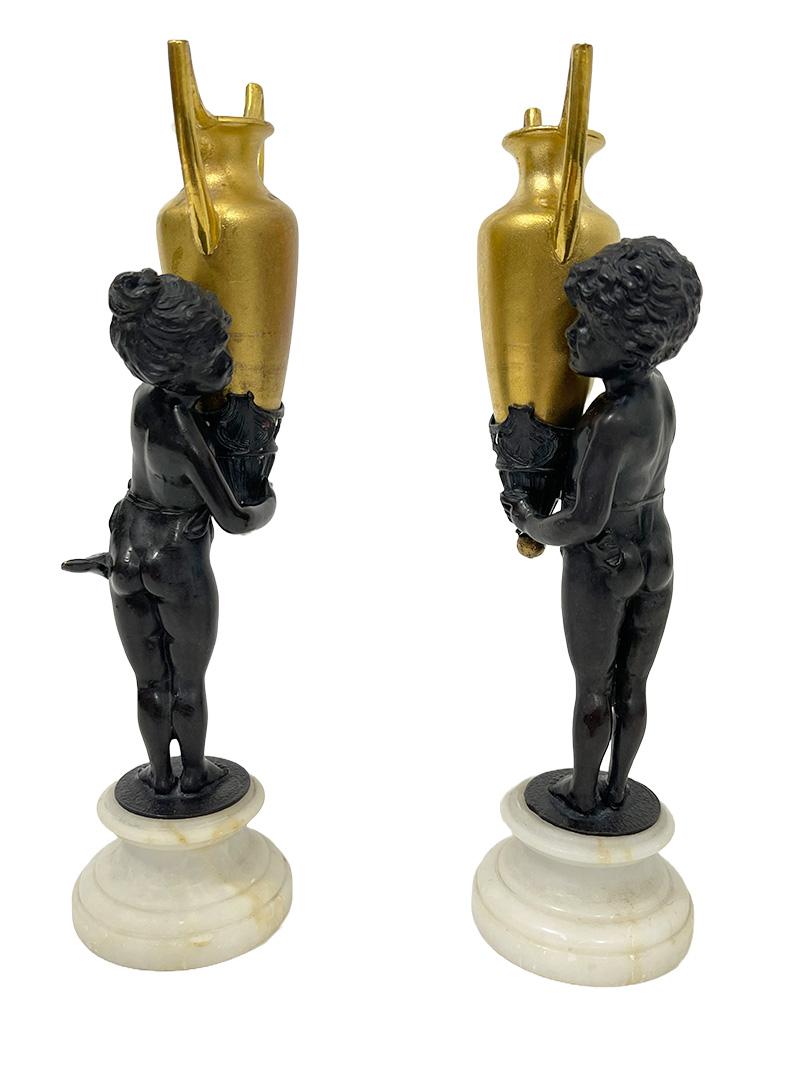 19th century small French bronze-gilt figurines, ca 1880

1880 small French bronze figurines.
A boy and a girl carrying an urn-shaped handled vase . Bronze figurines with gilt urn shaped handled vases, raised on a marble base. It is reminiscent