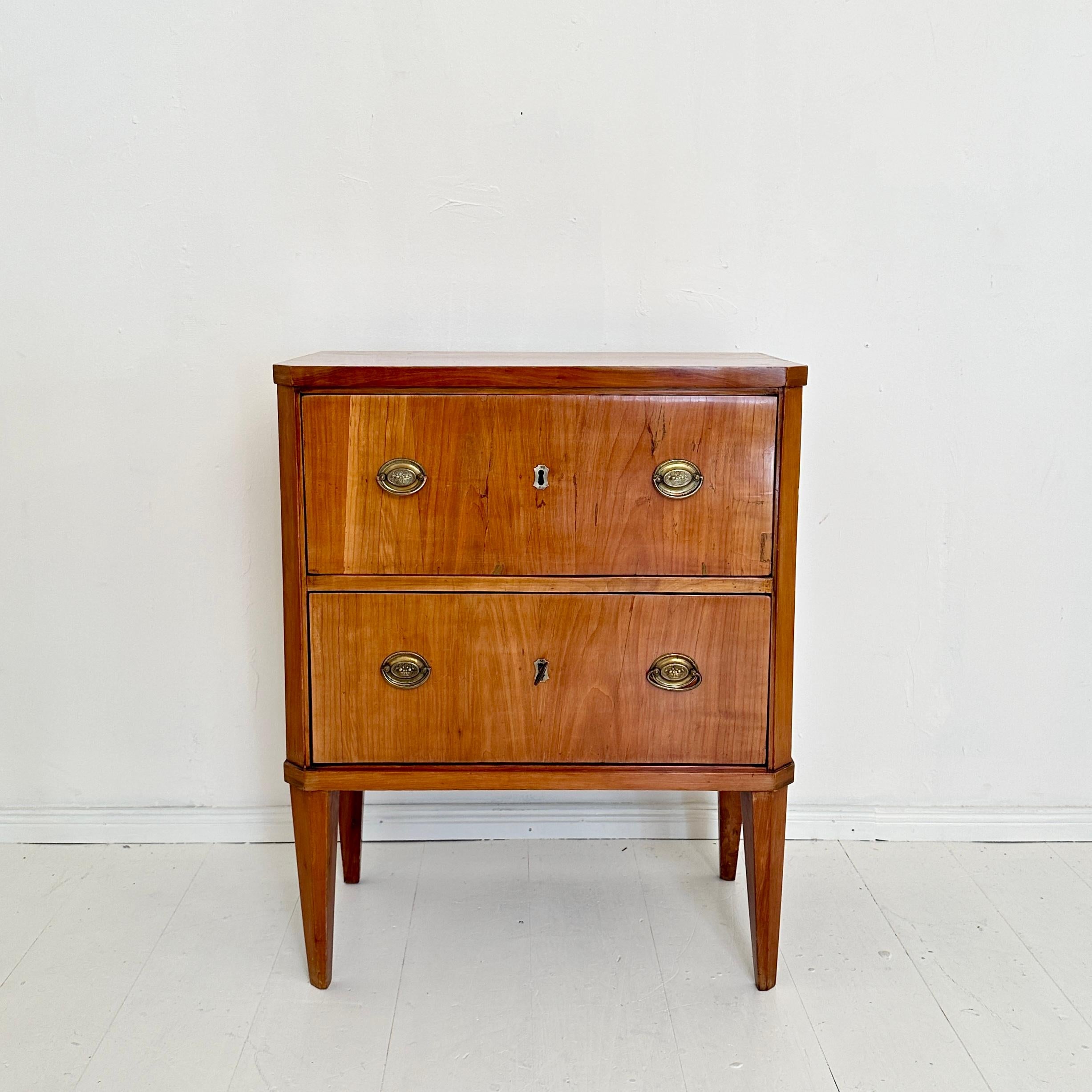 Diese exquisite kleine Biedermeier-Kommode aus der Zeit um 1820 in Deutschland zeigt die raffinierte Eleganz des Designs des frühen 19. Das aus hellem, rotbraunem Kirschbaumholz gefertigte Stück strahlt Wärme aus, wobei die natürliche Holzmaserung