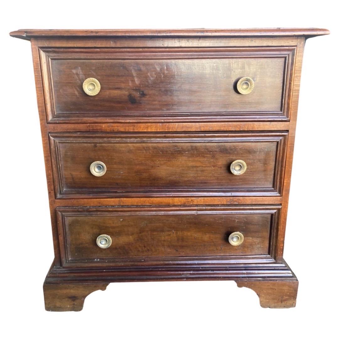 Small Comodino with three drawers hand-made in Italy in the mid to late 1800s using walnut. The small chest of drawers has very straight lines, nevertheless some movement is provided by molding placed around the drawer fronts. The top of the