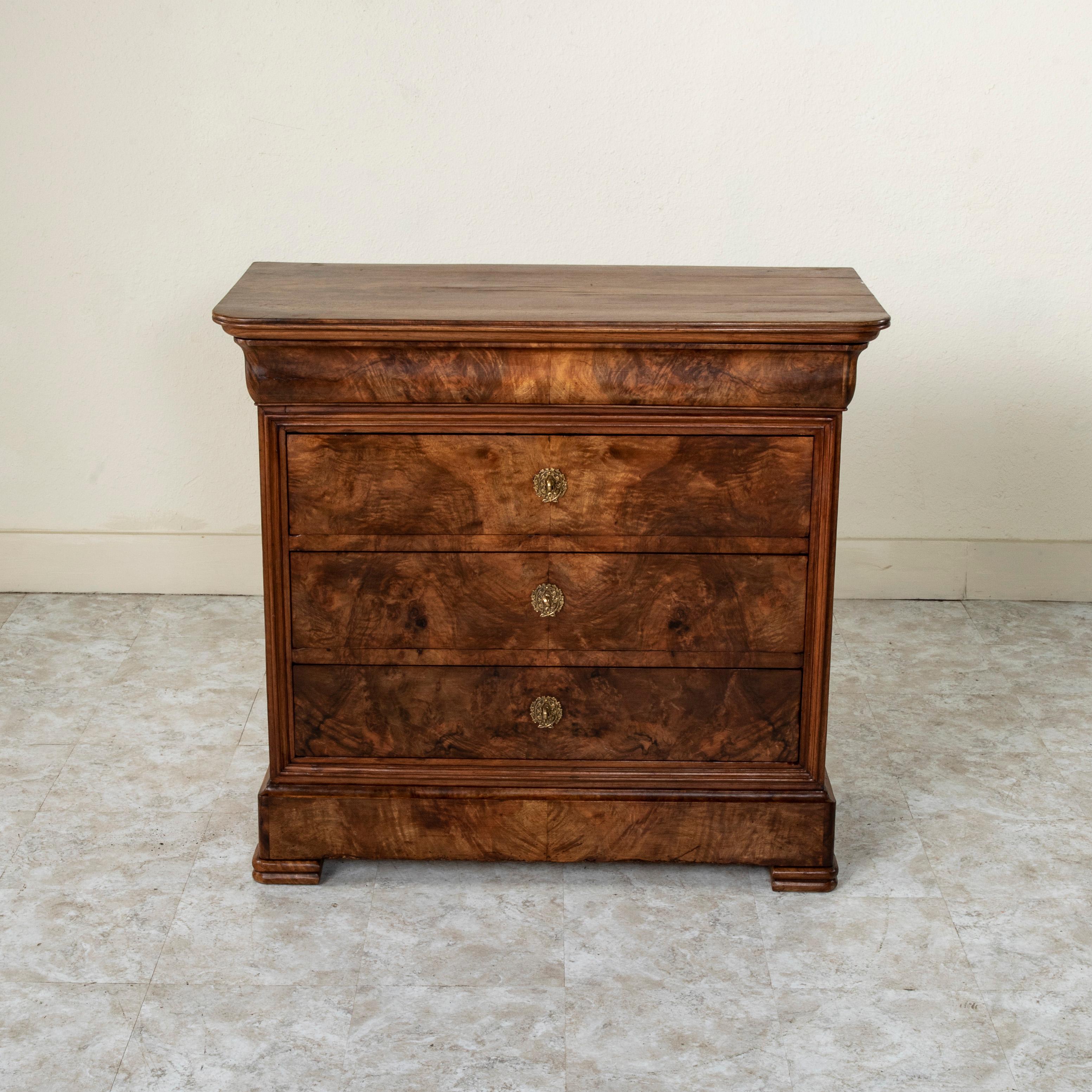 Unusual for its smaller scale with a 39.75 inch width, this quintessential Louis Philippe period commode or chest of drawers displays the exemplary craftsmanship of the early nineteenth century with a facade of book matched walnut and solid walnut
