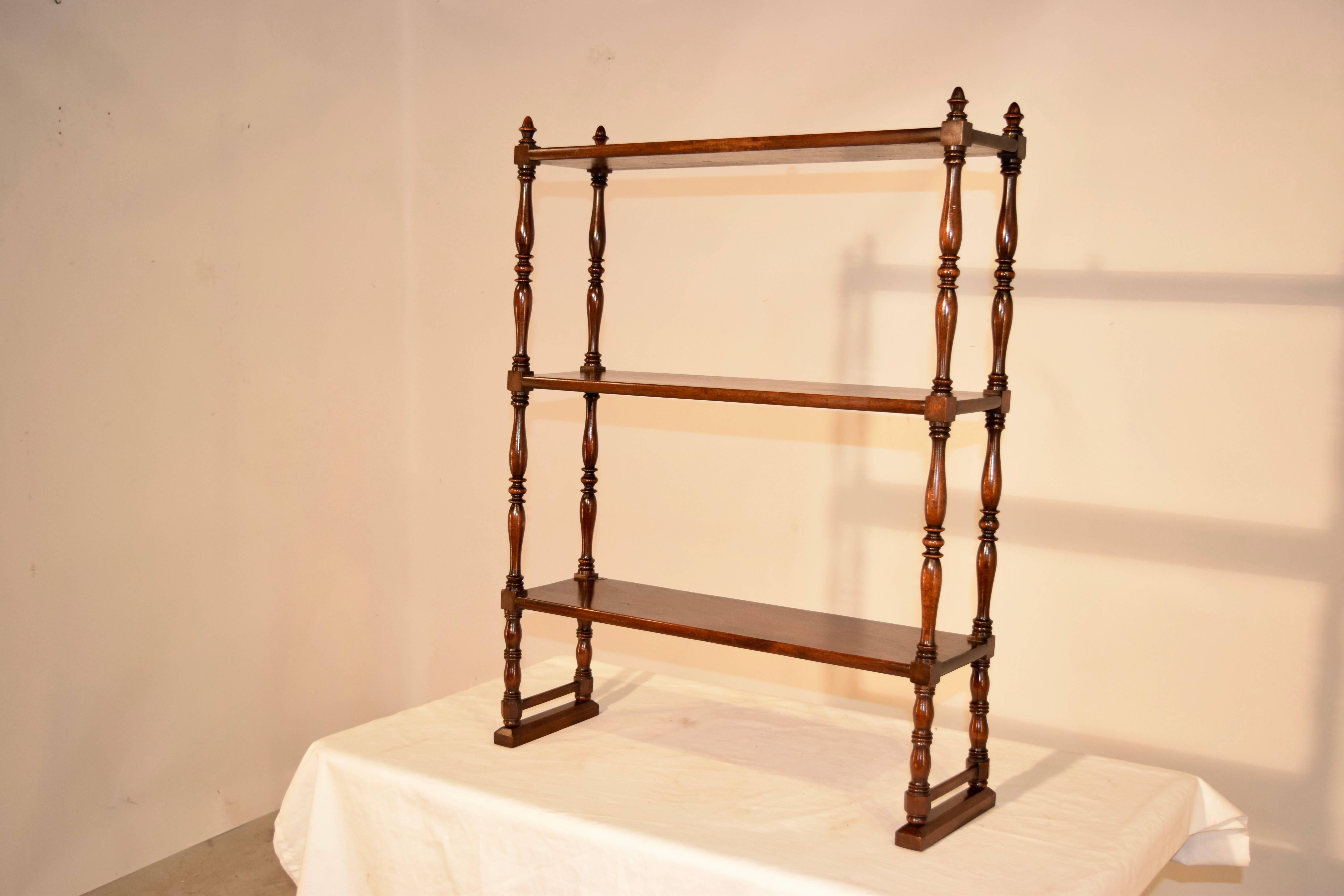 19th century mahogany small standing shelf from England. It has three shelves, one which has a small old repair, and separated by hand-turned shelf supports. Great size.