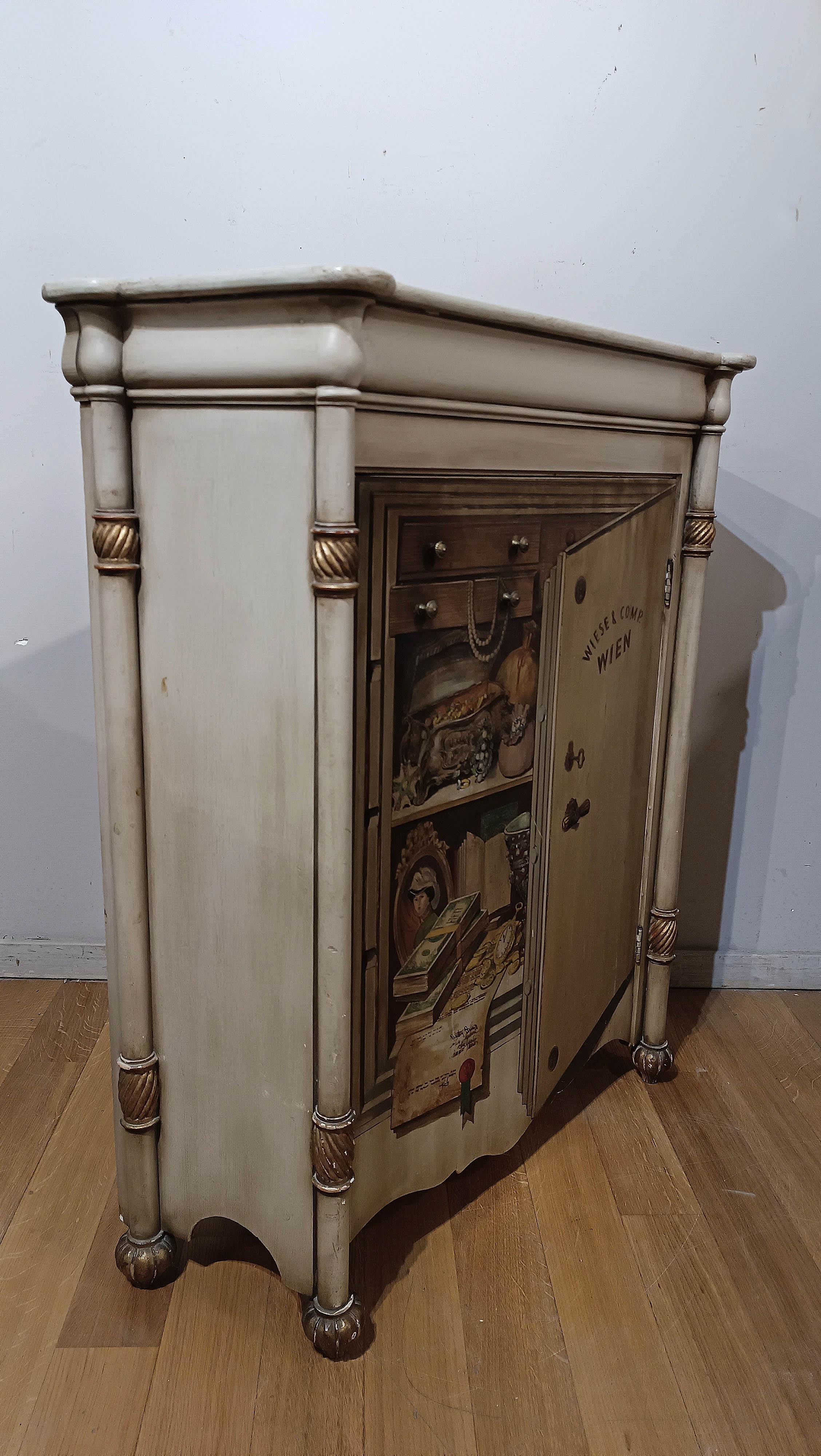 Elegant trompe l'oeil small sideboard, made of painted poplar wood and then gilded with gold leaf. The golden details are found in the capitals of the corner columns, and in the straight knob-shaped feet. But the real peculiarity of this sideboard