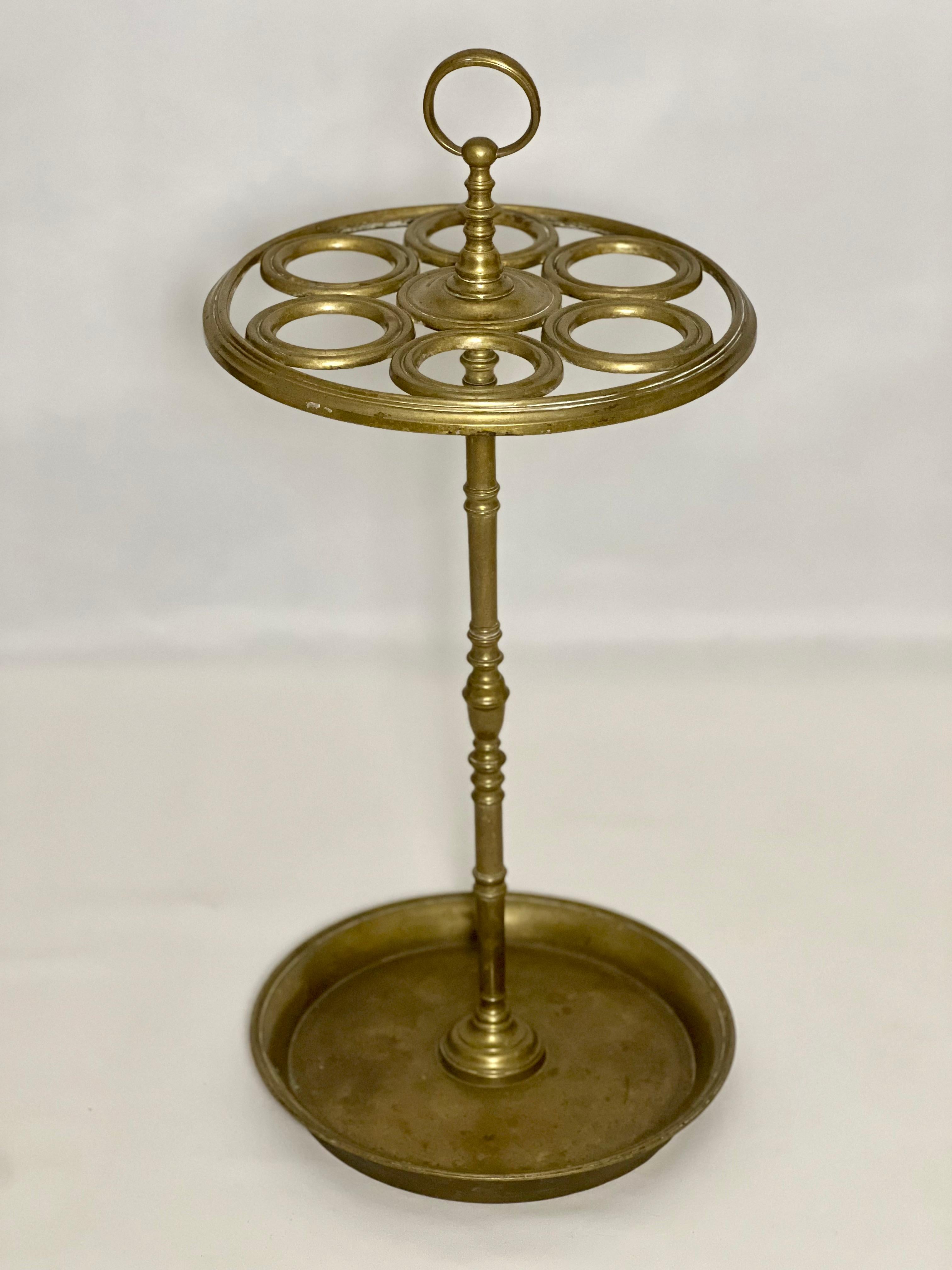 19th century solid brass umbrella stand.

Beautiful six section holder featuring a ring shaped handle, finely turned support and circular base with raised rim.  Simple in design yet quite unique. It has a pleasantly aged patina and good weight. 