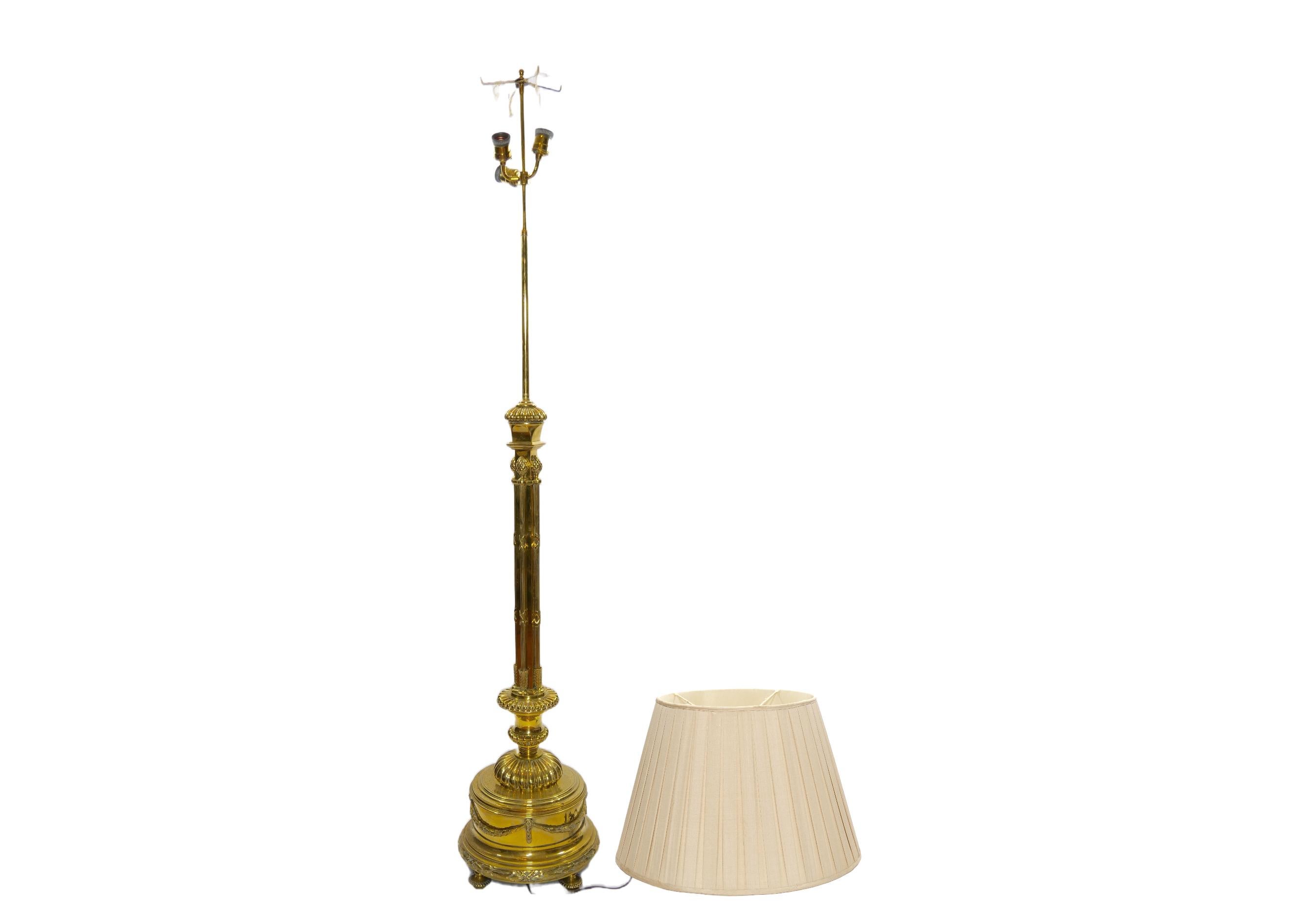 Late 19th century hand crafted gilt solid brass with footed round base Italian floor lamp. The floor lamp features a very slender shape with a heavy footed base with exterior garland wreath design details . The lamp comes with a round linen pleated
