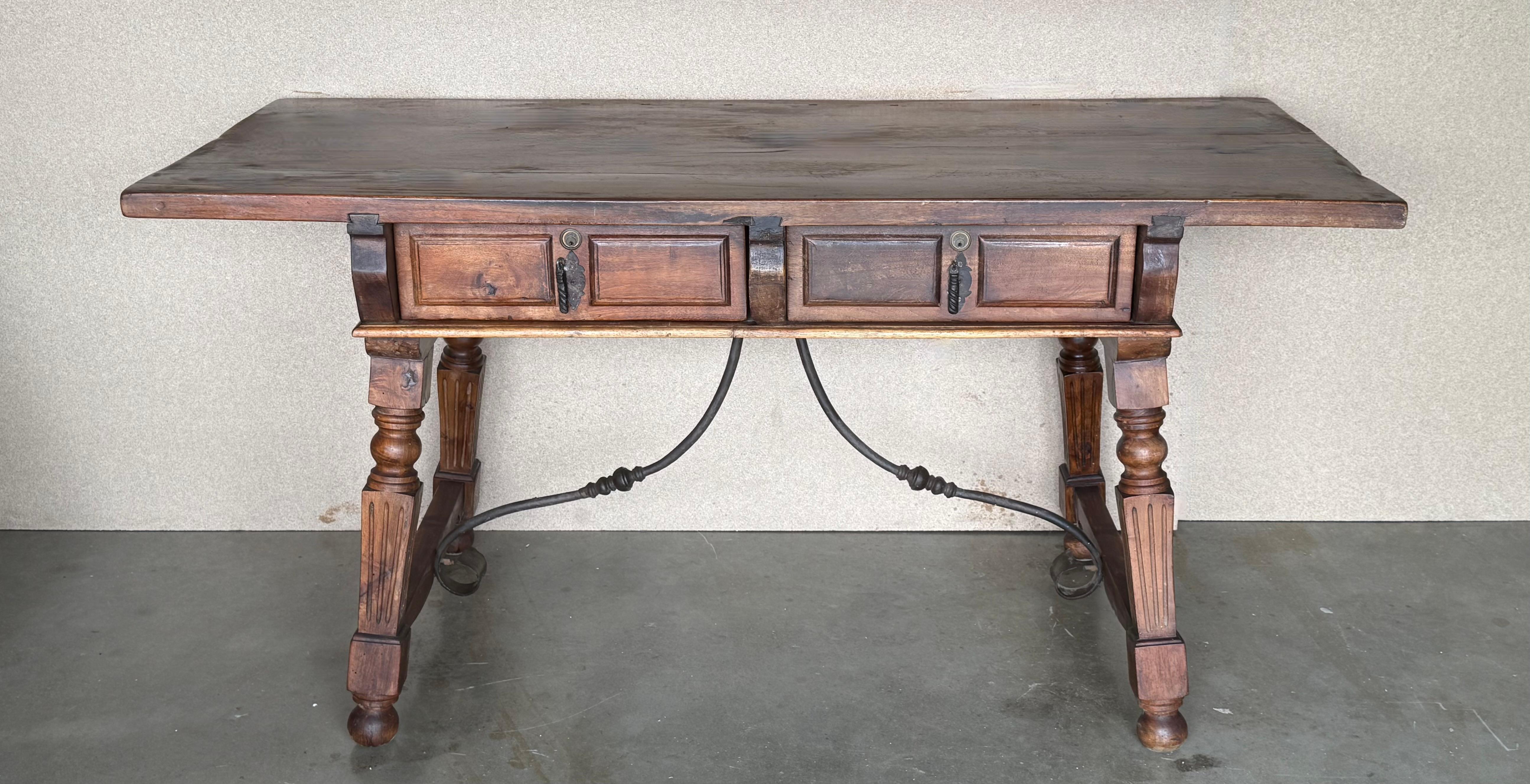 Height from the floor to the bottom drawer: 23.42in

An 19th century Spanish baroque desk, or writing table made of solid oak with fluted shaped legs joined by solid wood stretched. Two drawers with original iron drawer pulls and two false drawers