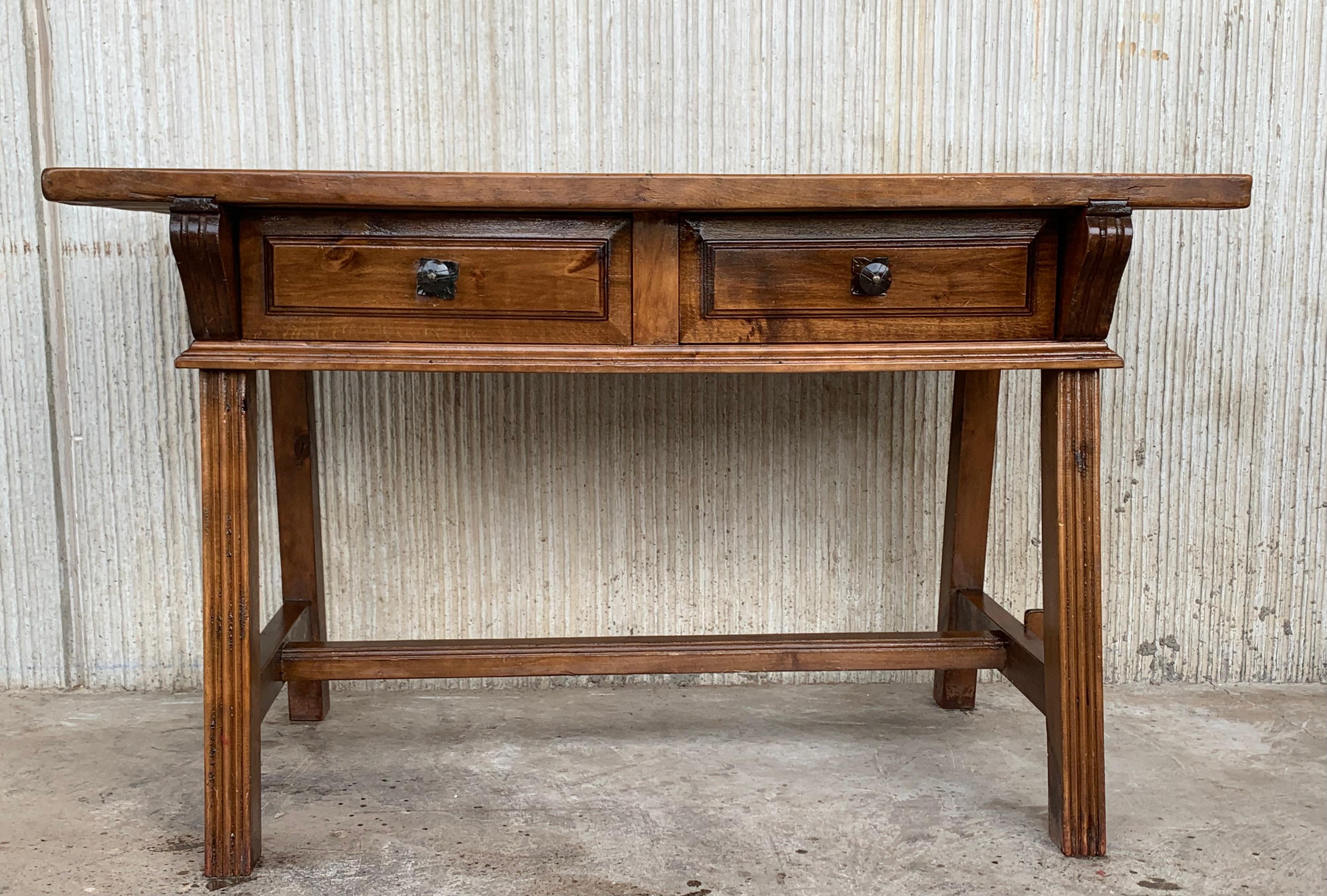 An 19th century Spanish baroque desk, or writing table made of solid oak with lyre shaped legs joined by solid wood stretched. Two drawers with original iron drawer pulls. The top is made from a single plank of oak and is slightly warped. Beautiful