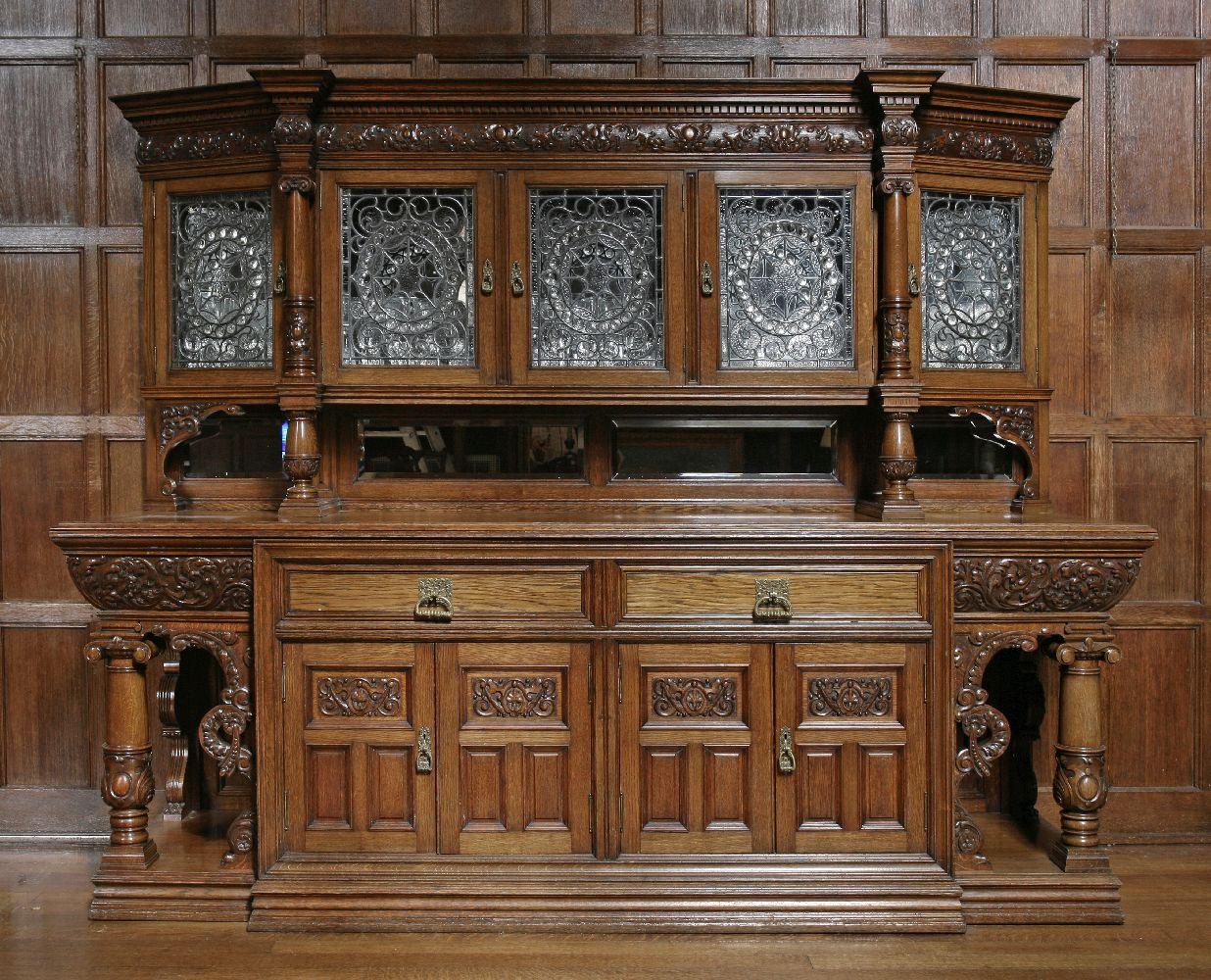 For sale is an extraordinary Victorian oak sideboard, with a raised back having a dentil and carved frieze over five leaded glass doors and turned ionic columns. The base with two drawers and two paneled doors, one enclosing a cellaret, within
